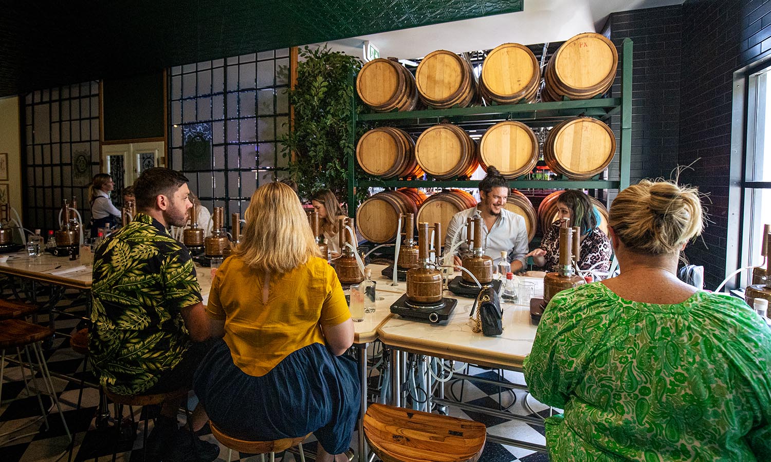 A group of people sit around a table drinking gin at Brisbane Distillery Company.