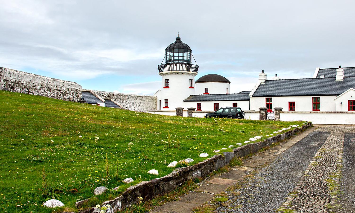 The iconic lighthouse of Clare Island, surrounded by lush green grass.