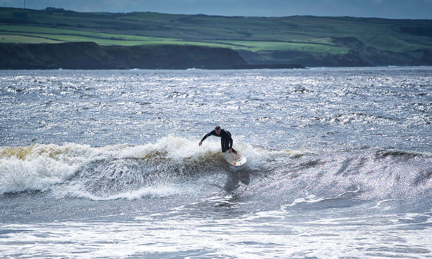 A lone surfer catches waves off the Sligo Coast.