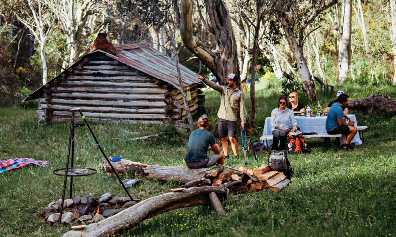 A group of people sit around a temporary campsite in the Victorian bush.