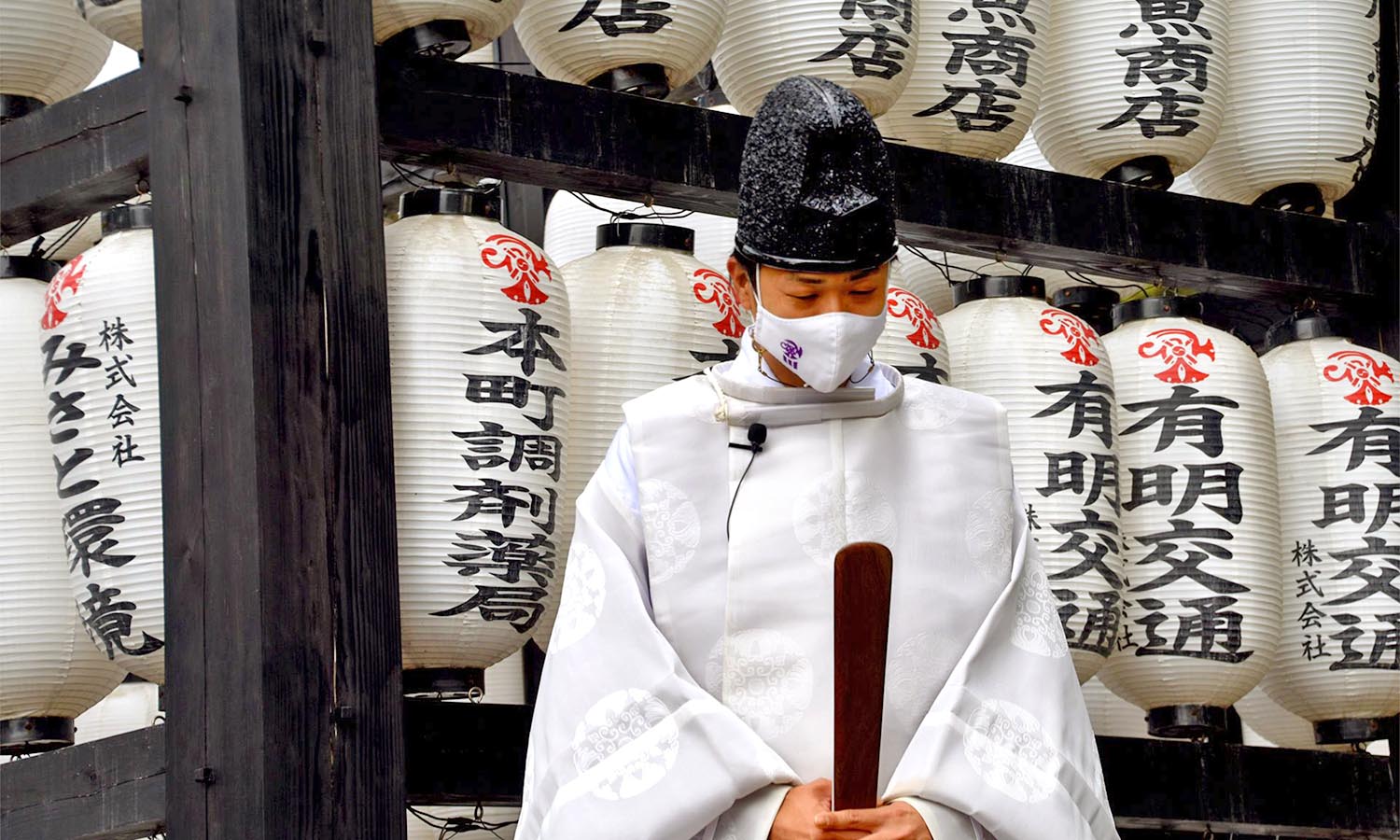 A traditional Japanese priest bows his head in front of Sanbashira Shrine.