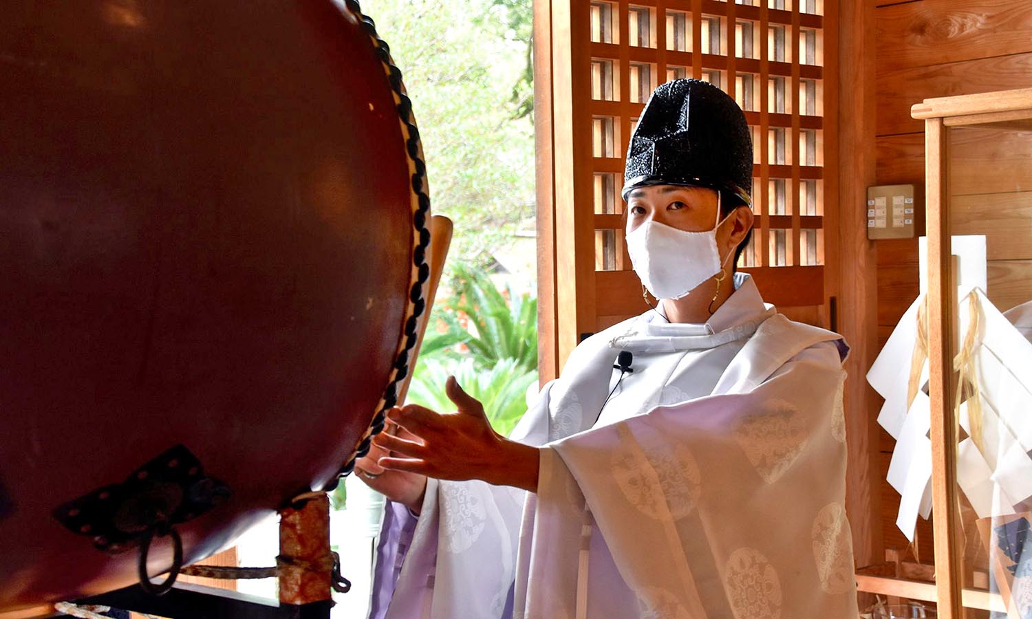 A traditional Japanese priest hits a gong at temple. 