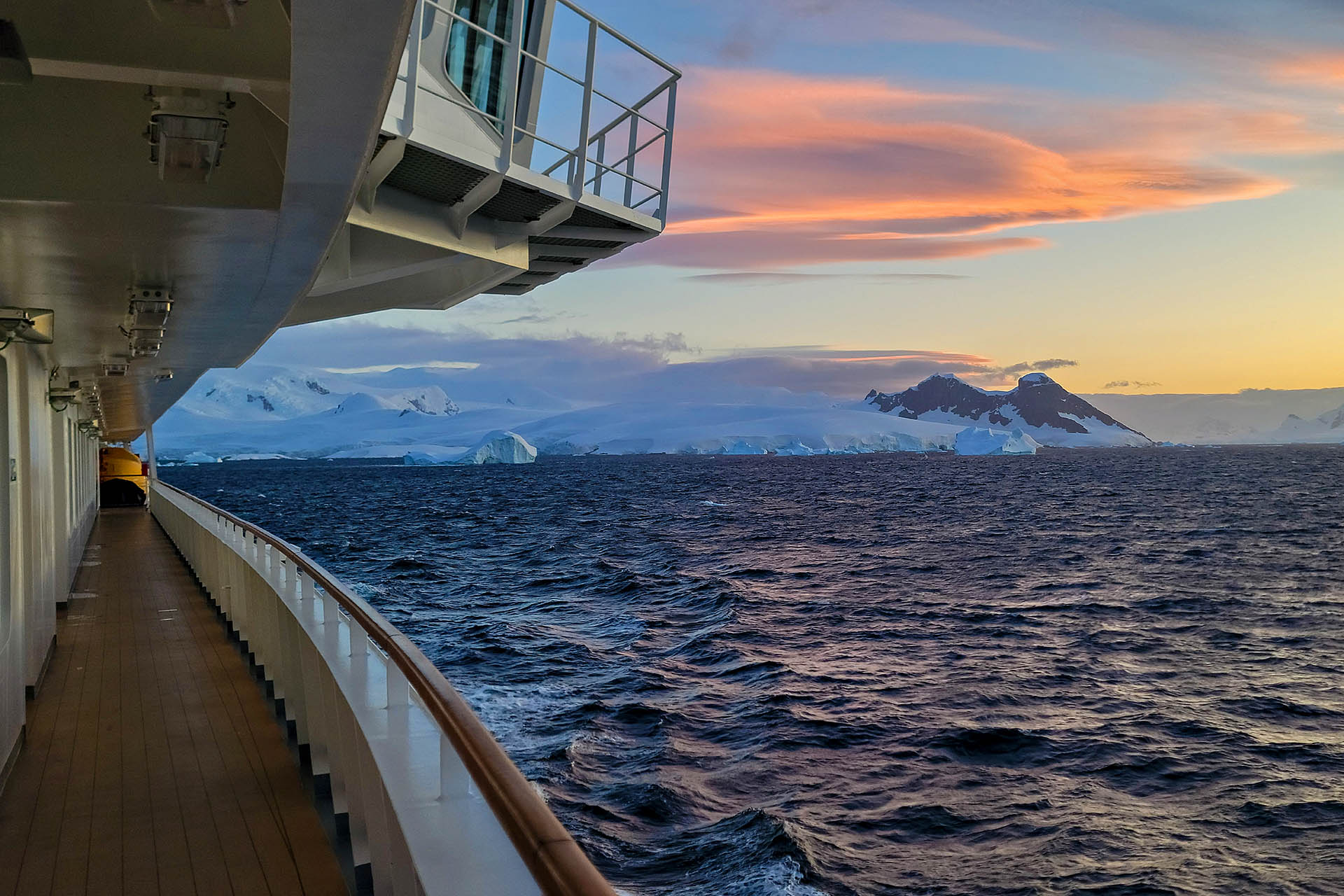 The side of an expedition ship as the sun sets on a day in Antarctica.