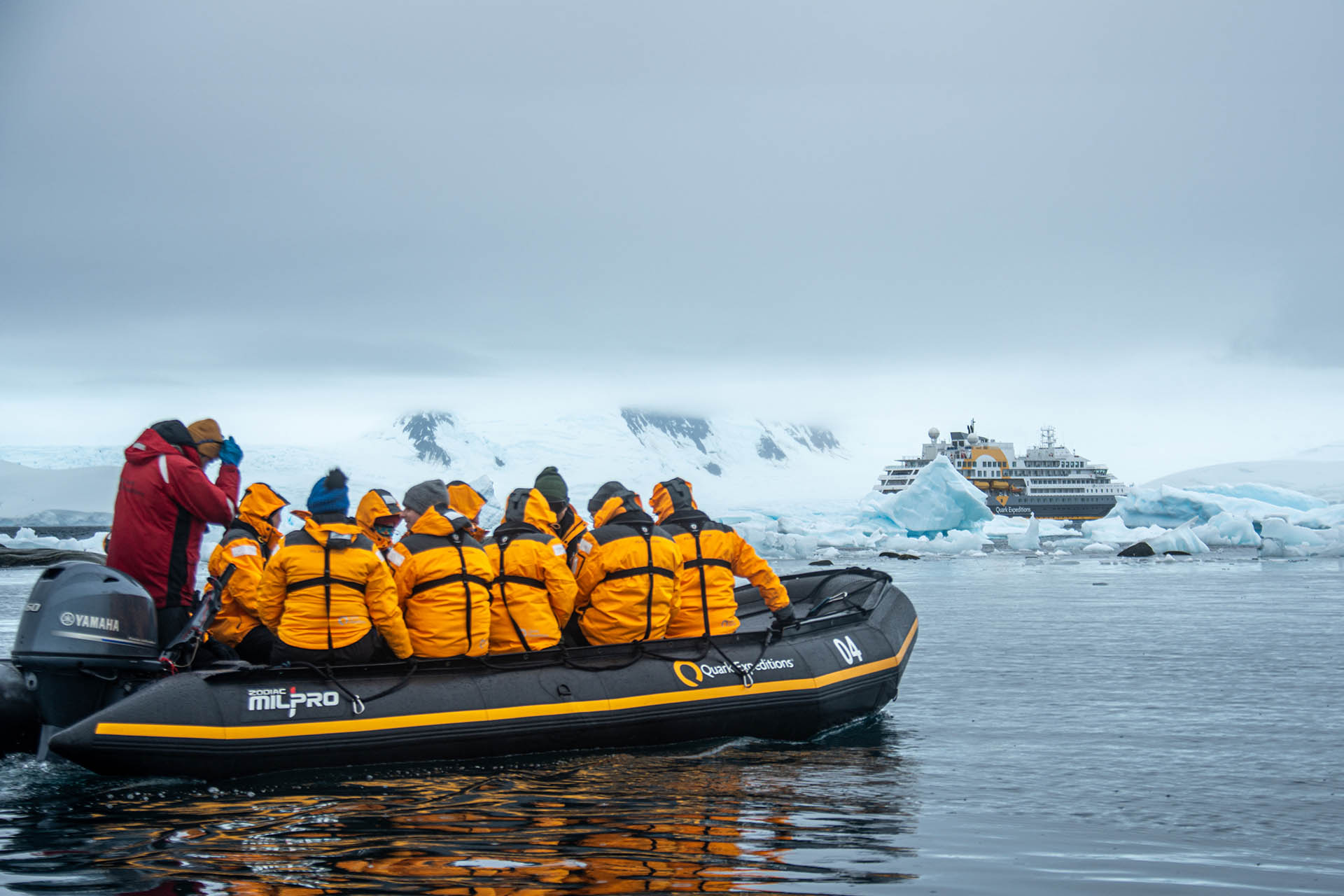 A group of people leave an expedition ship behind on a smaller zodiac boat in Antarctica.