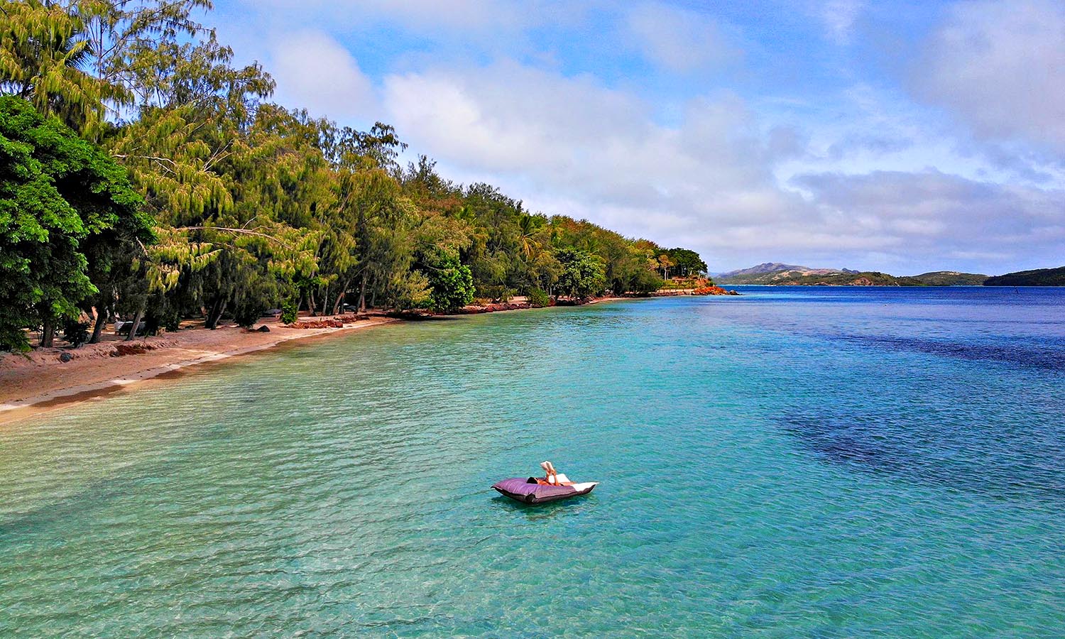 A woman lies on an inflatable bed just off the shore of Turtle Island in Fiji.