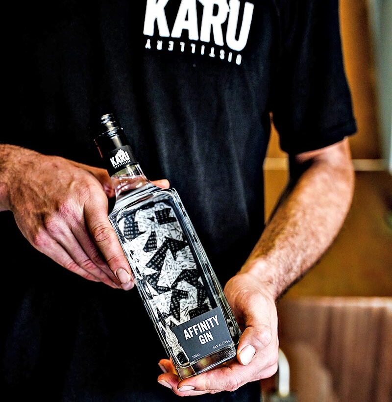 A man holding a bottle of Affinity Gin. 