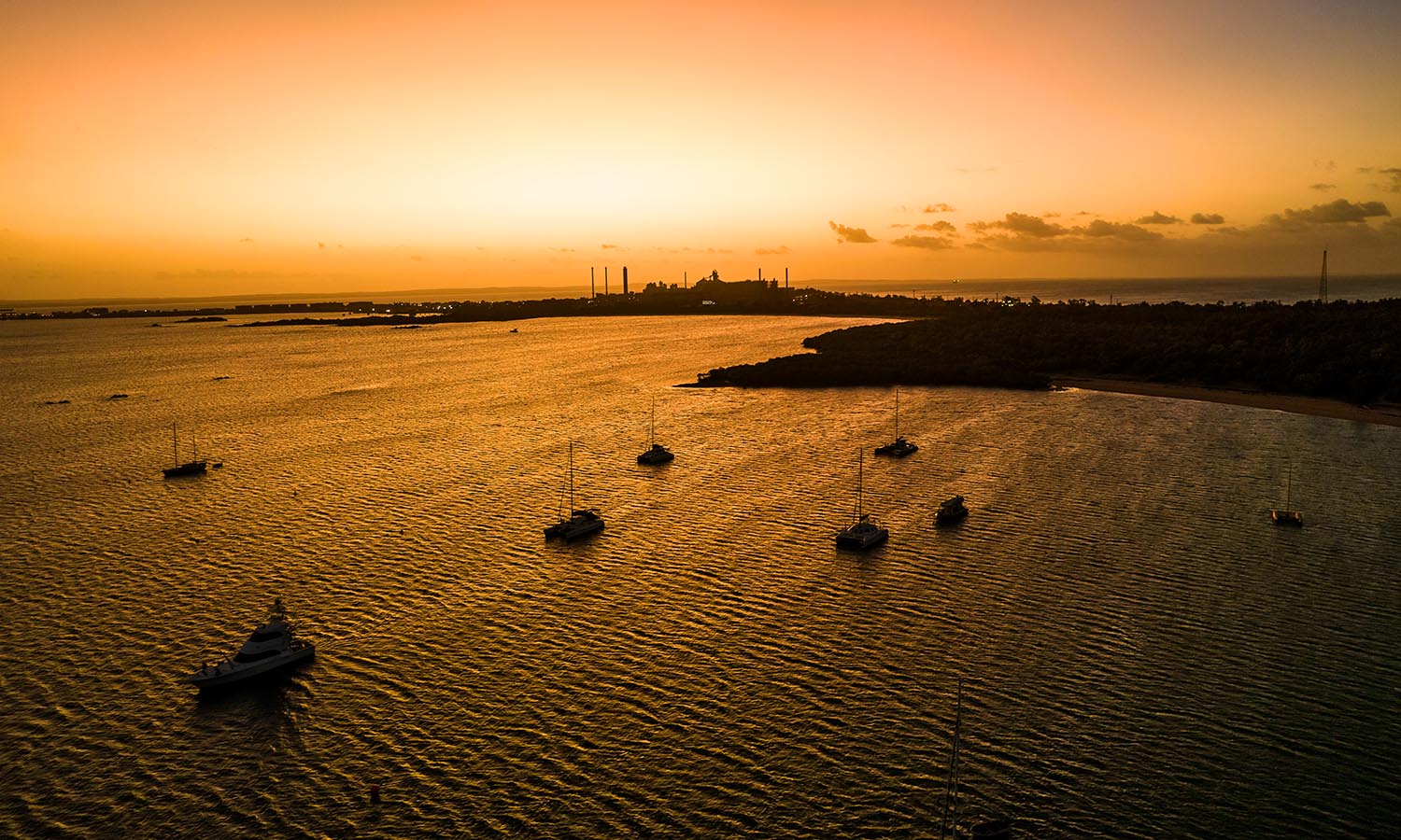 Boats docked in the water next to the Gove Boat Club at sunset.