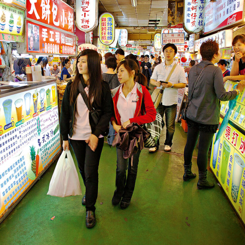 Local women walking through the crowded Shilin Night Market in Taipei.
