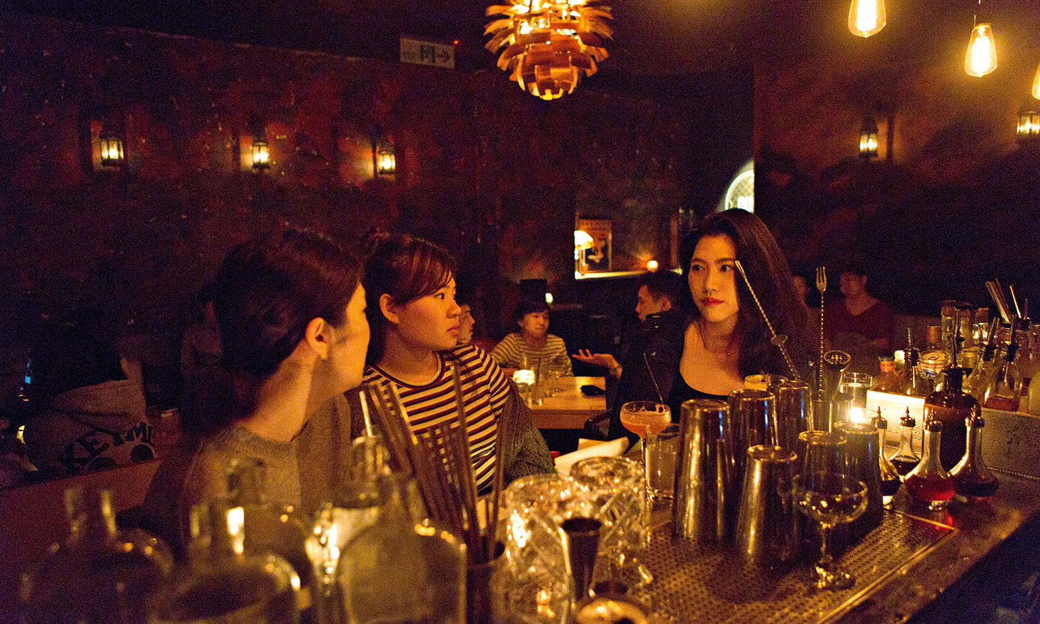 A few local women chatting together at a dimly lit cocktail bar in Taipei.