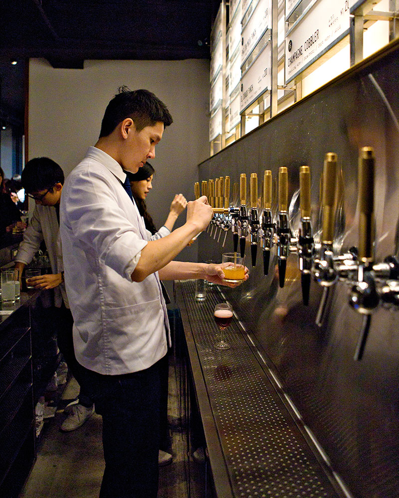 A man pours a cocktail out of a tap at a bar in Taipei.