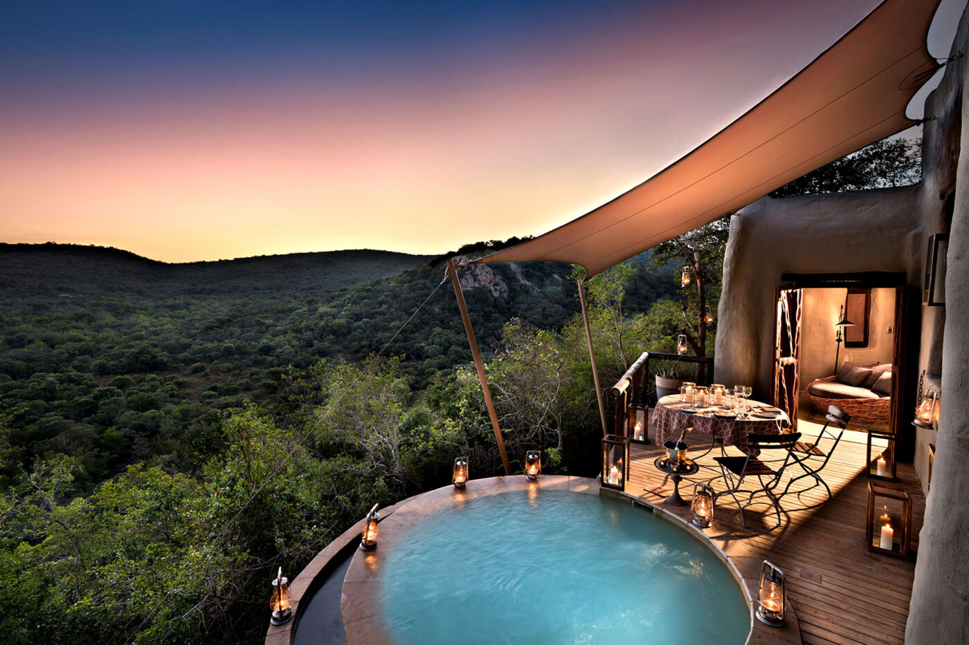 A small pool overlooks the Phinda Private Game Reserve, beside a small table set up for dinner.