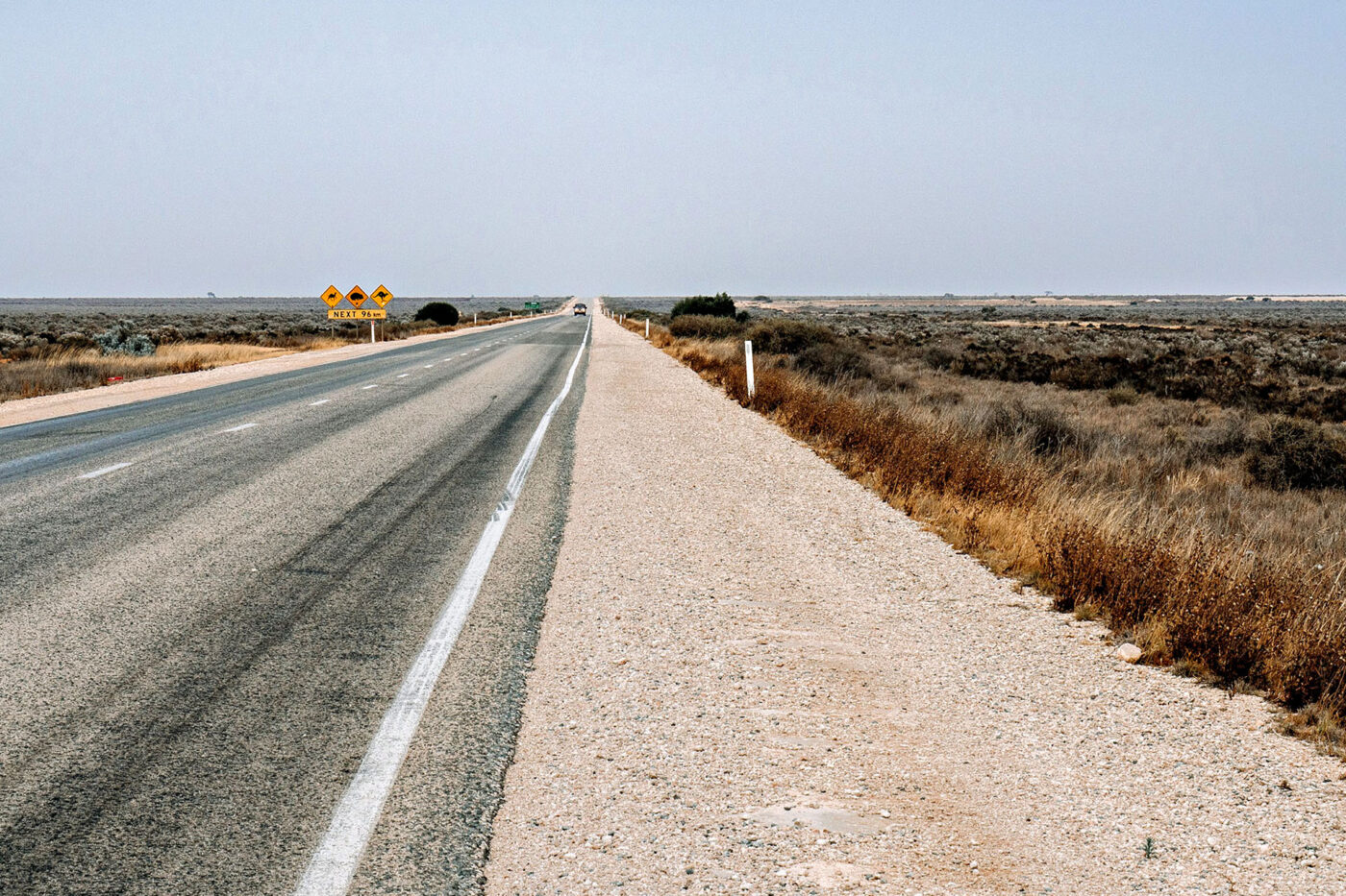 A car drives on its own down a highway surrounded by desert.