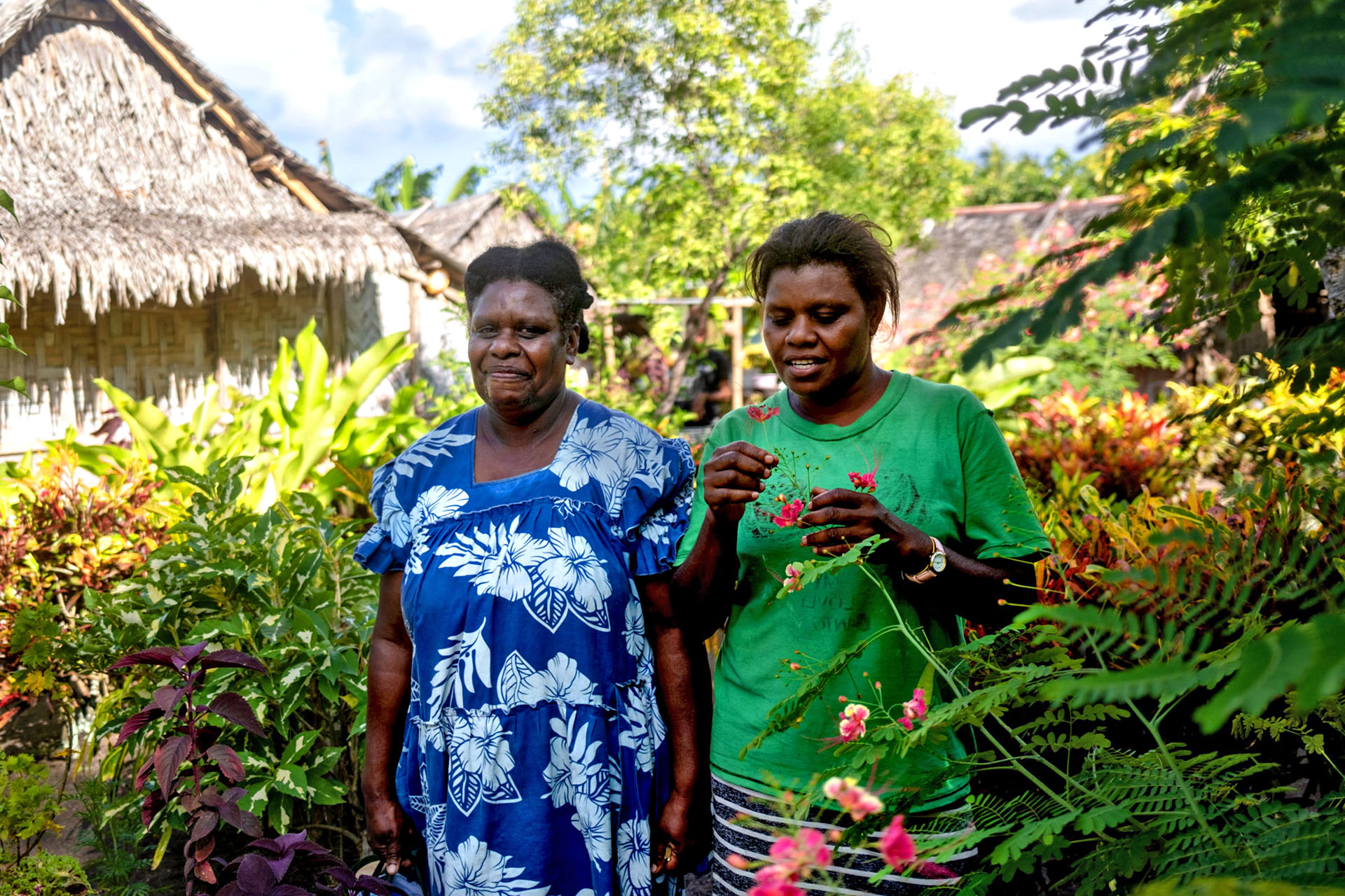 Two local women are standing outside in their village in Vanuatu.