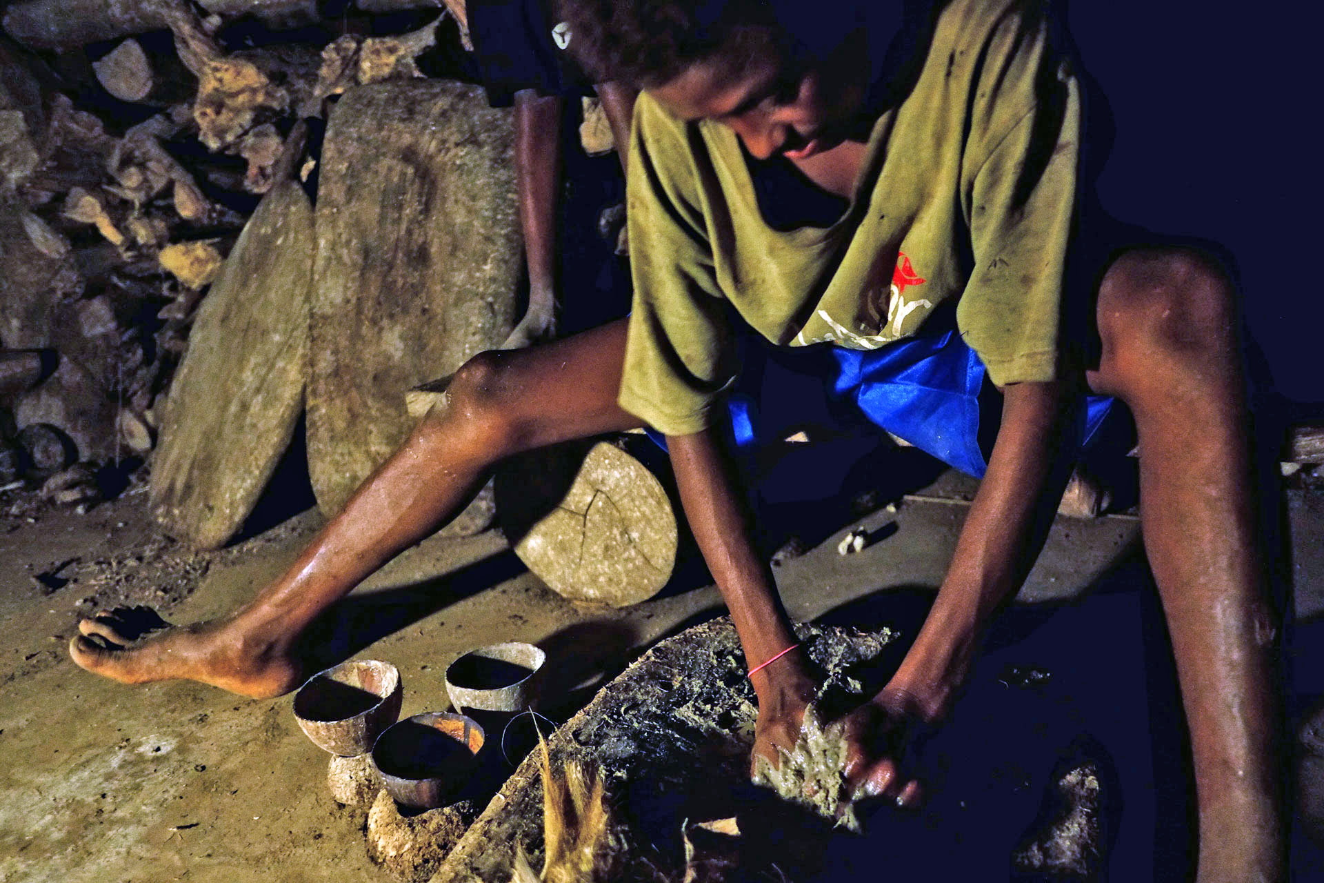A young local Vanuatuan boy grinds the kava root into a paste.