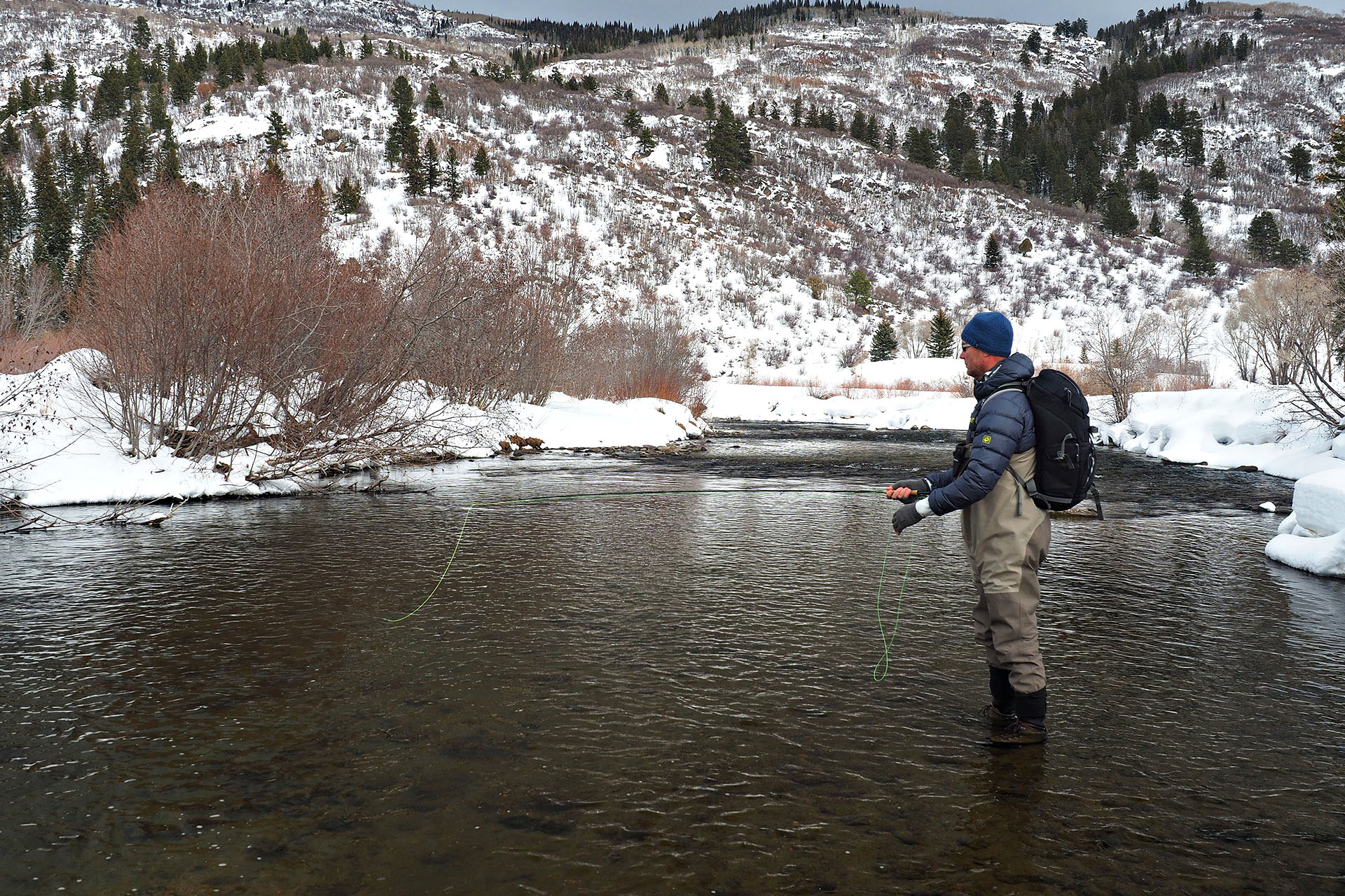 A person standing in a river fly fishing in Steamboat Springs.