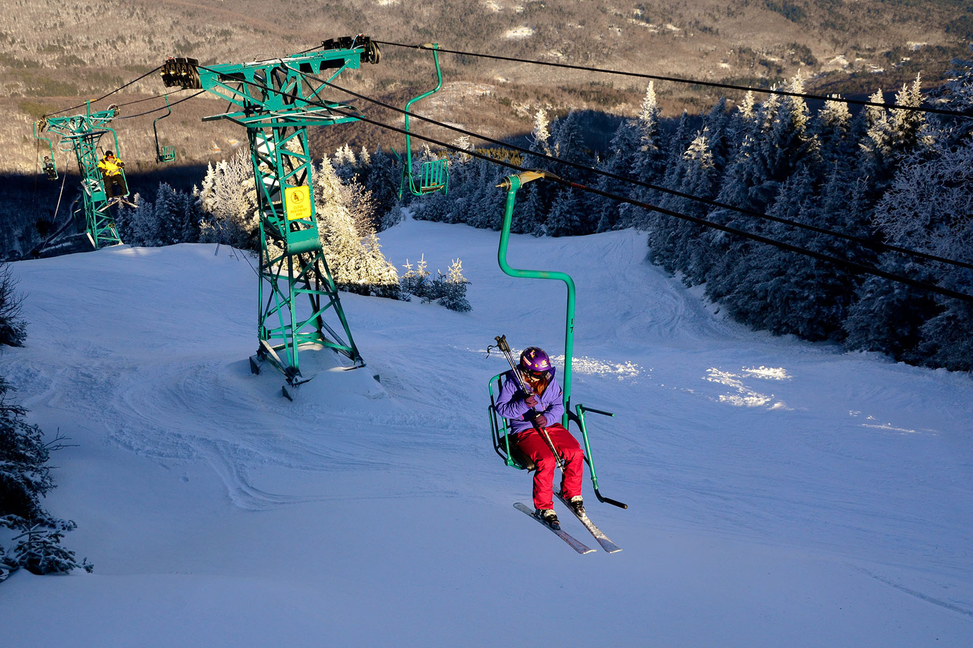 A lone skiier on a chairlift above lots of white, fluffy snow.