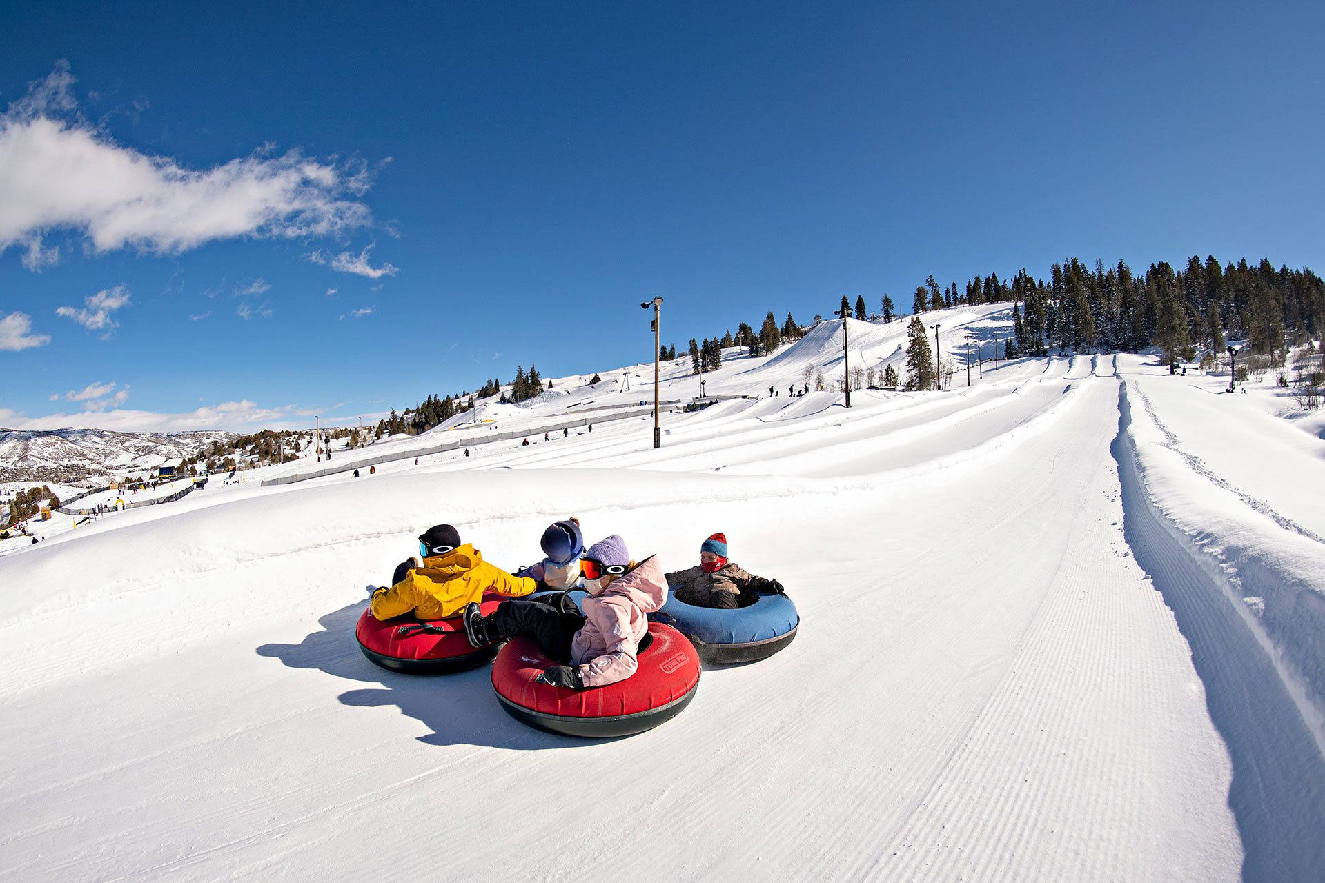 A group of kids in inflatable donut rings going down an icy slide of snow.