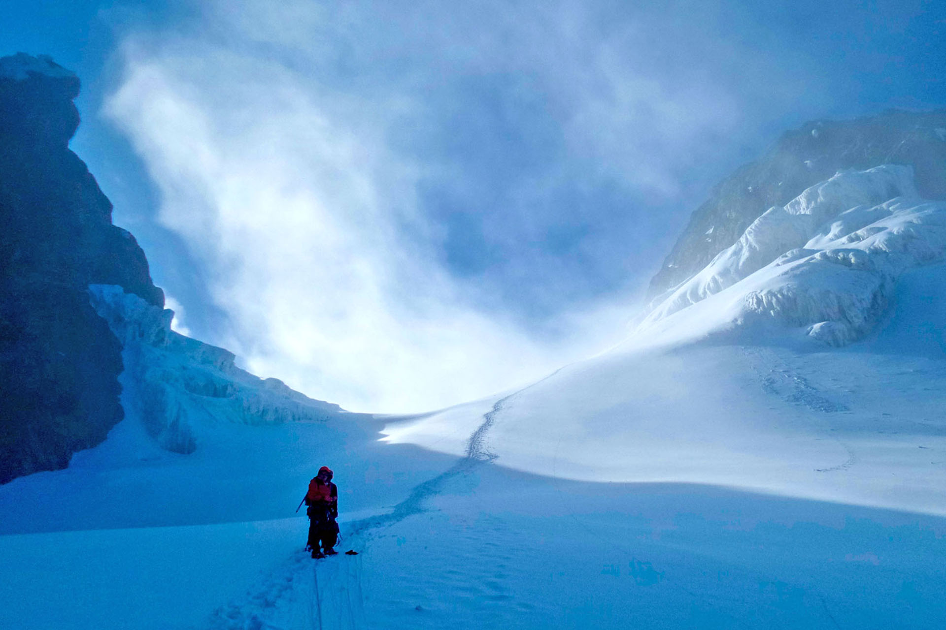 A couple of hikers are embarking on a snowy trek through the Rwenzori Mountains National Park on a sunny day.