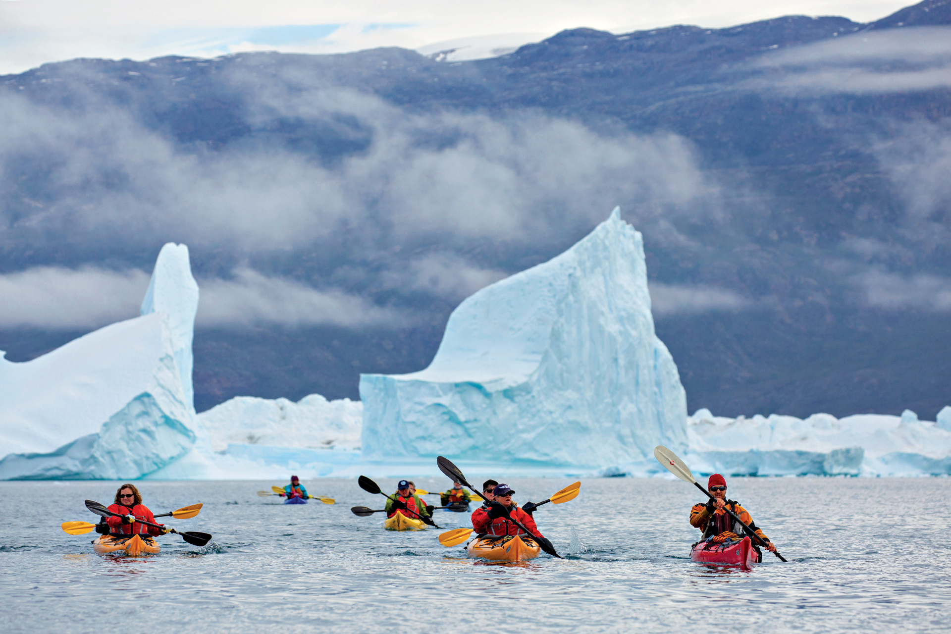 A photo puts the size of the icebergs into perspective as kayakers cruise past.