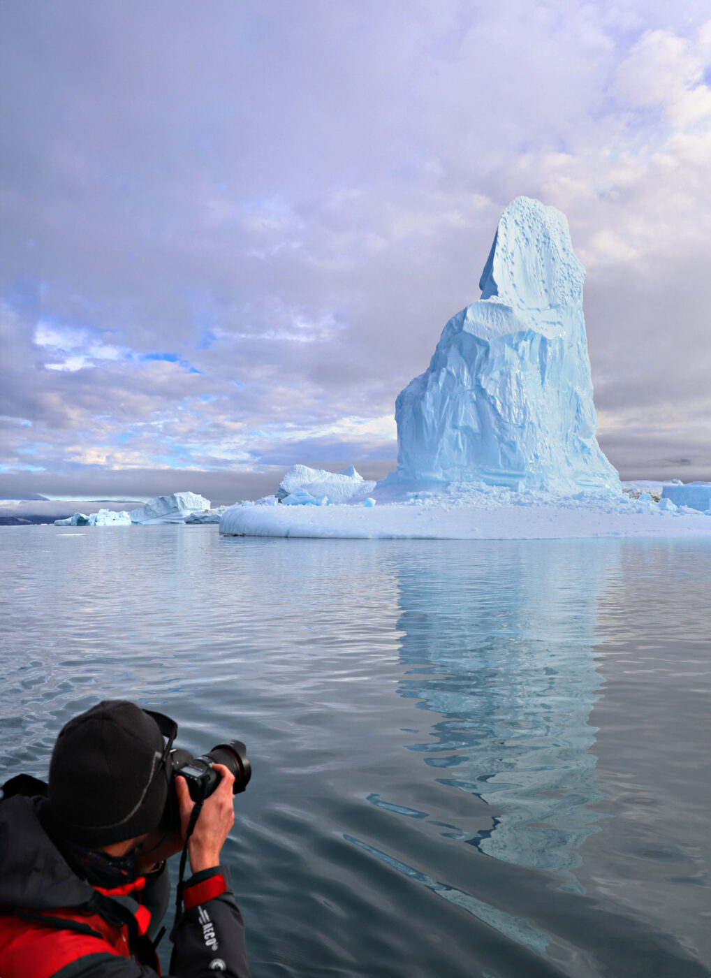A photo puts the size of the icebergs into perspective as kayakers cruise past.