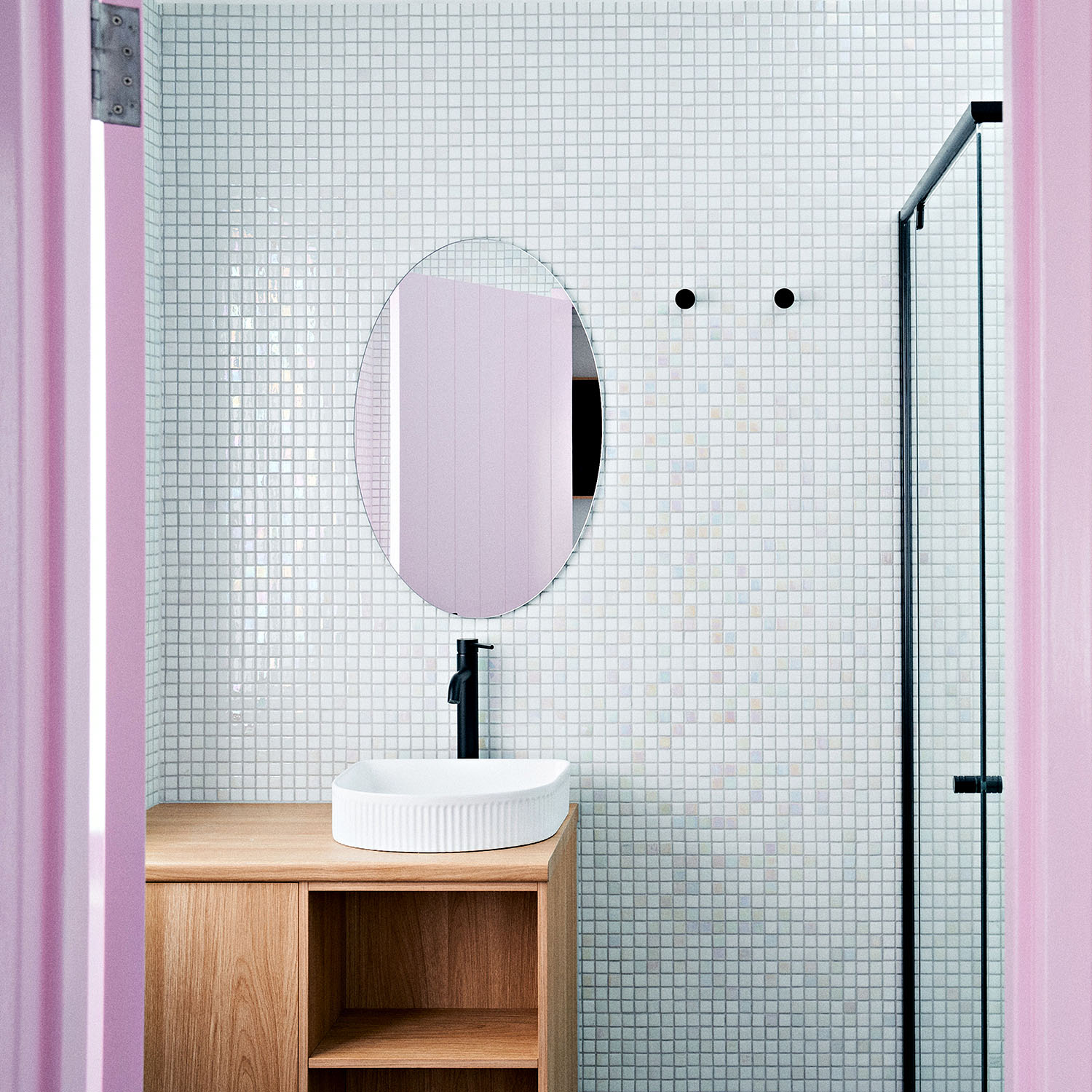 A tidy and clean bathroom featuring small square tiles and pops of pink. 