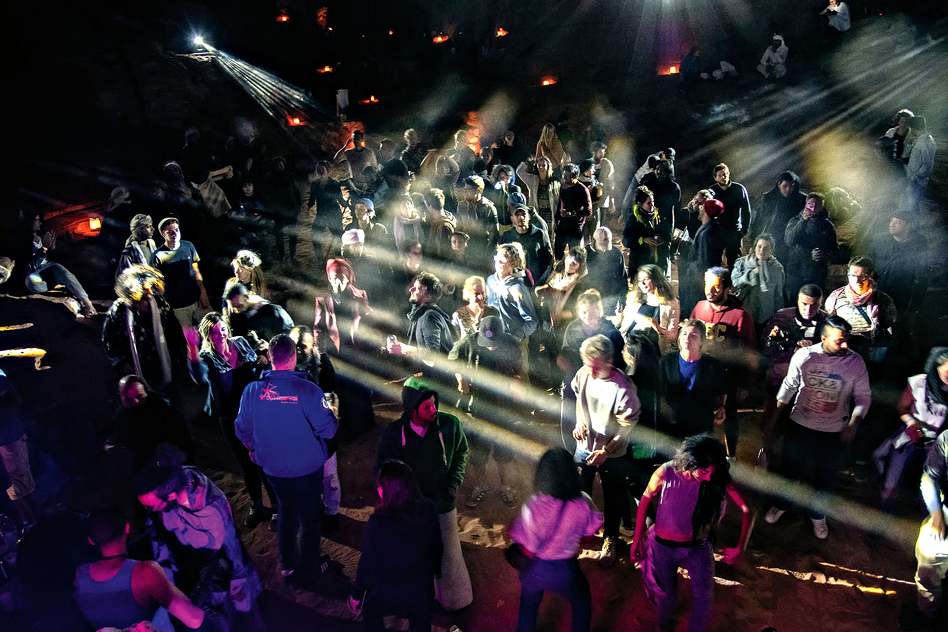 People dance to the music while surrounded by the sandstone and granite rock of the desert.