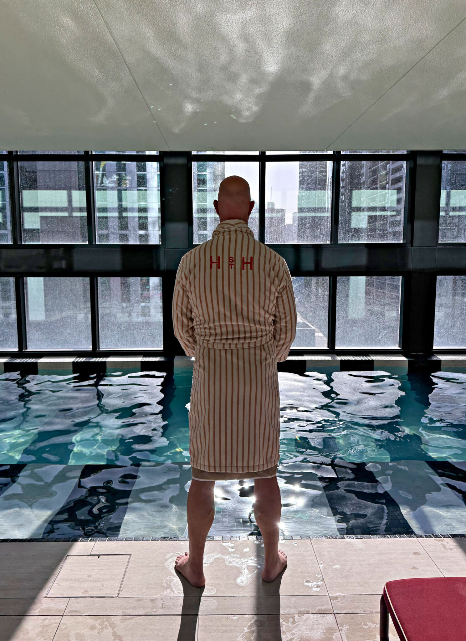 Guest relaxing beside the indoor swimming pool at Hannah St Hotel wellness centre in Melbourne.
