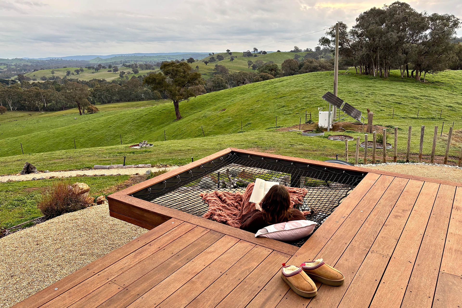Suspended outdoor hammock at Karak Eco Lodge overlooking rolling farmland in Victoria High Country.