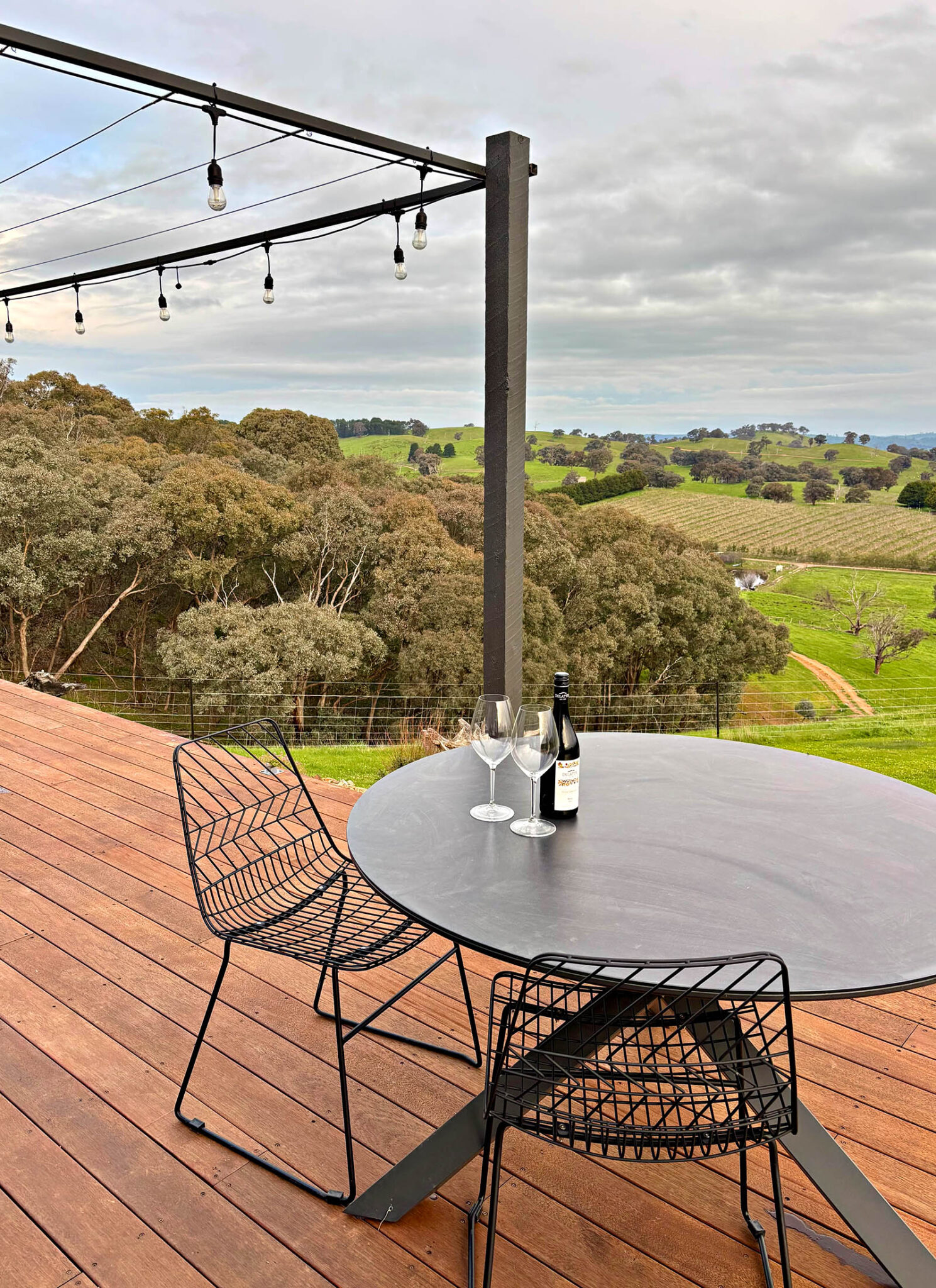 Outdoor dining deck at Karak Eco Lodge with vineyard and valley views in Victoria High Country.