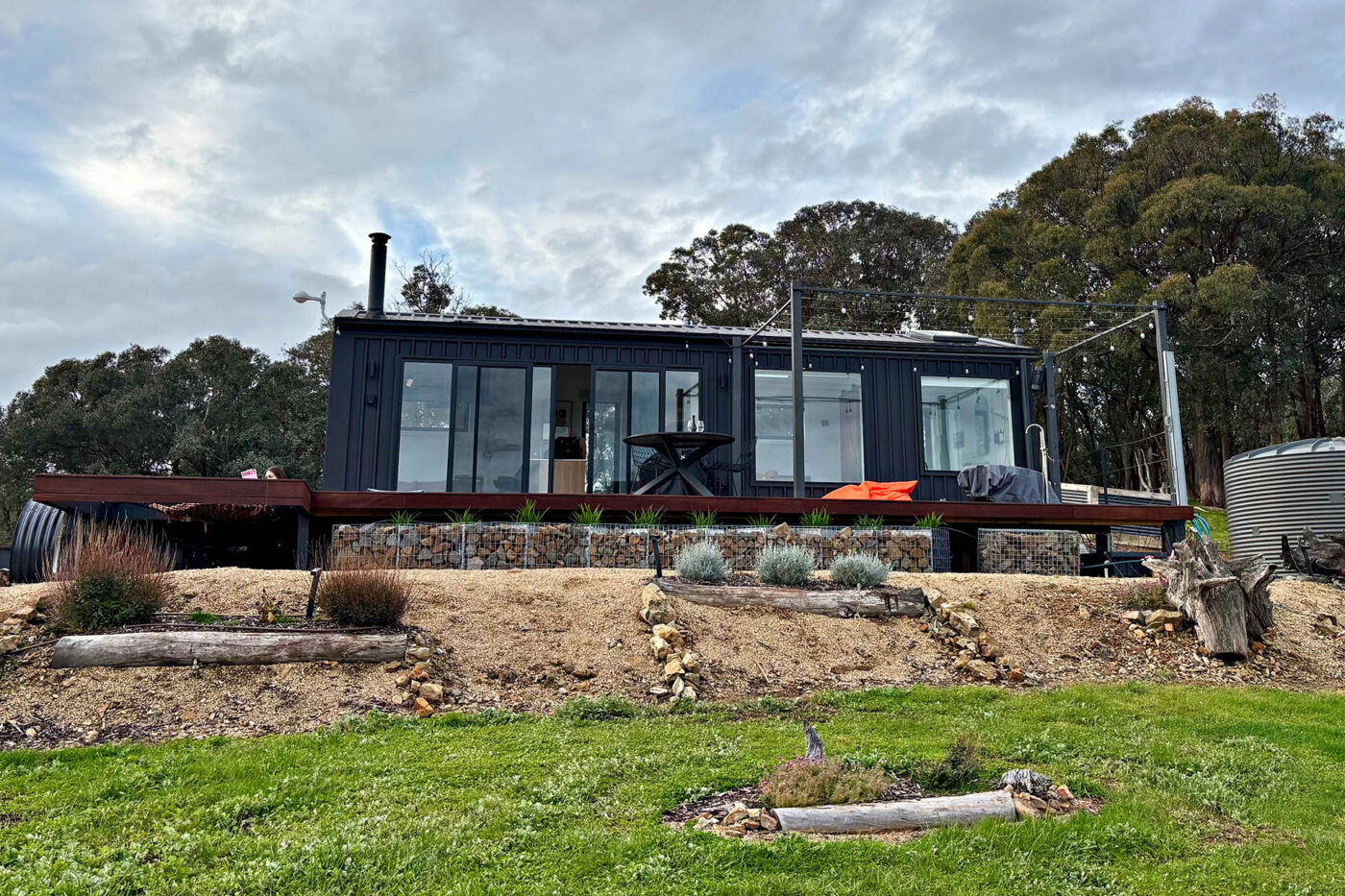 Rear view of Karak Eco Lodge showcasing the outdoor deck, hammock, hot tub and bushland surrounds in Victoria High Country.