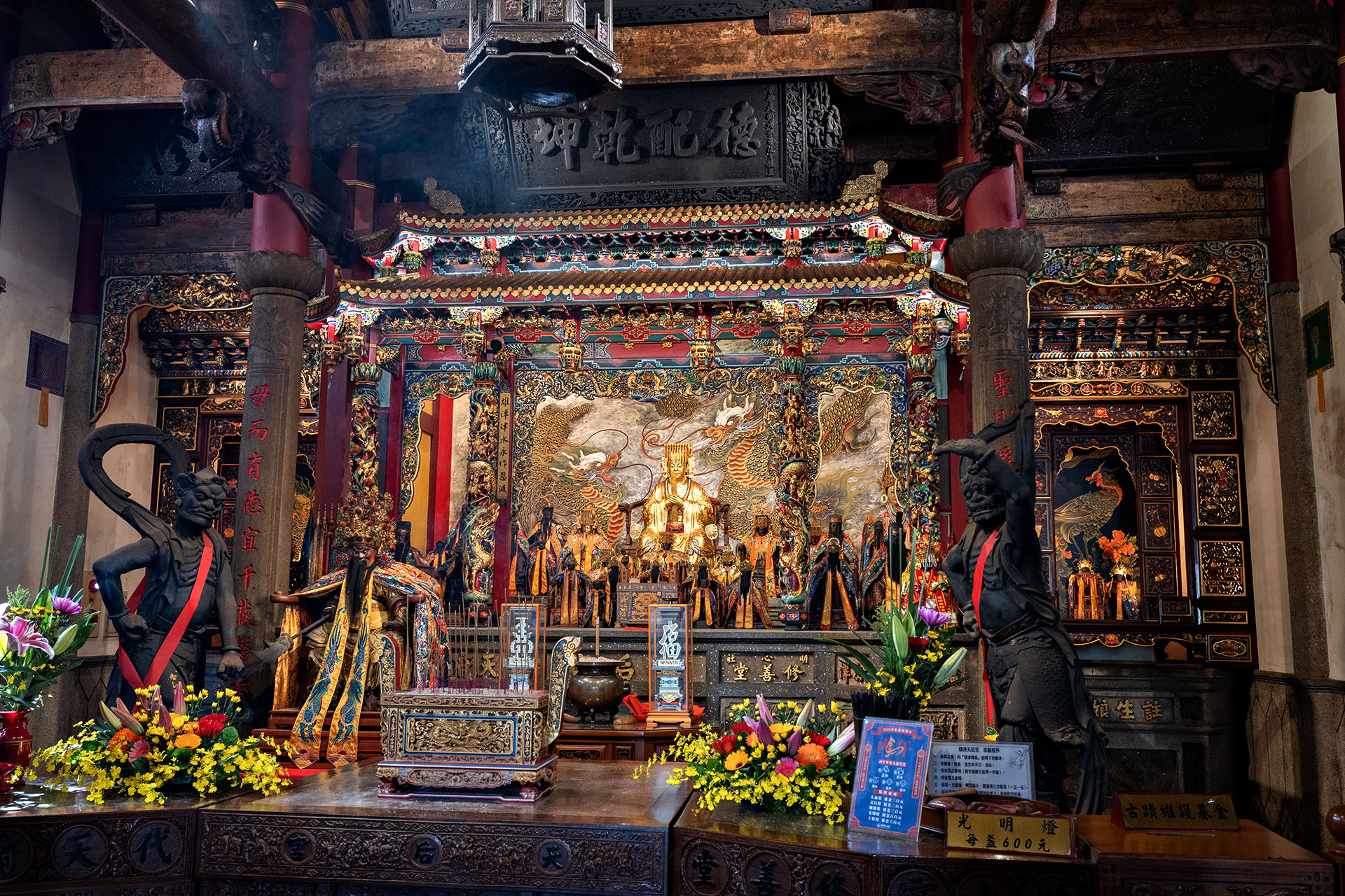 Ornate interior of a traditional Taiwanese temple decorated with colourful carvings and golden statues.