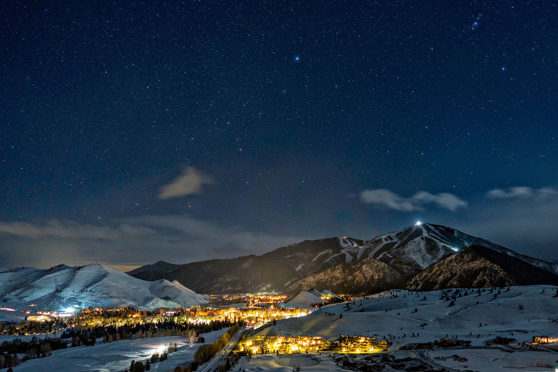 Snow-covered Sun Valley ski resort illuminated beneath a star-filled night sky in Idaho, USA.
