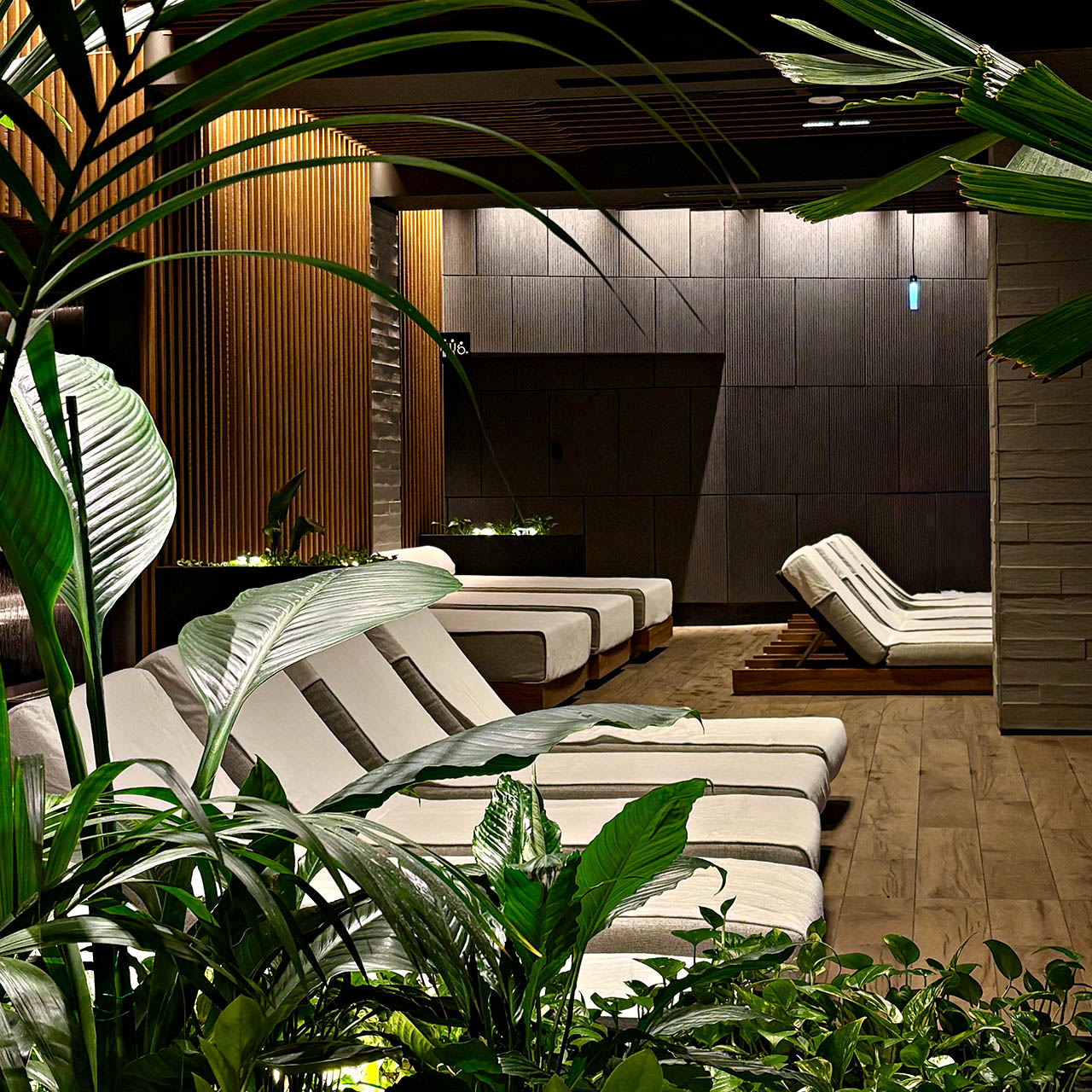 Relaxation lounge at Bamford Wellness Spa inside 1 Hotel Melbourne with daybeds, timber finishes and lush greenery.