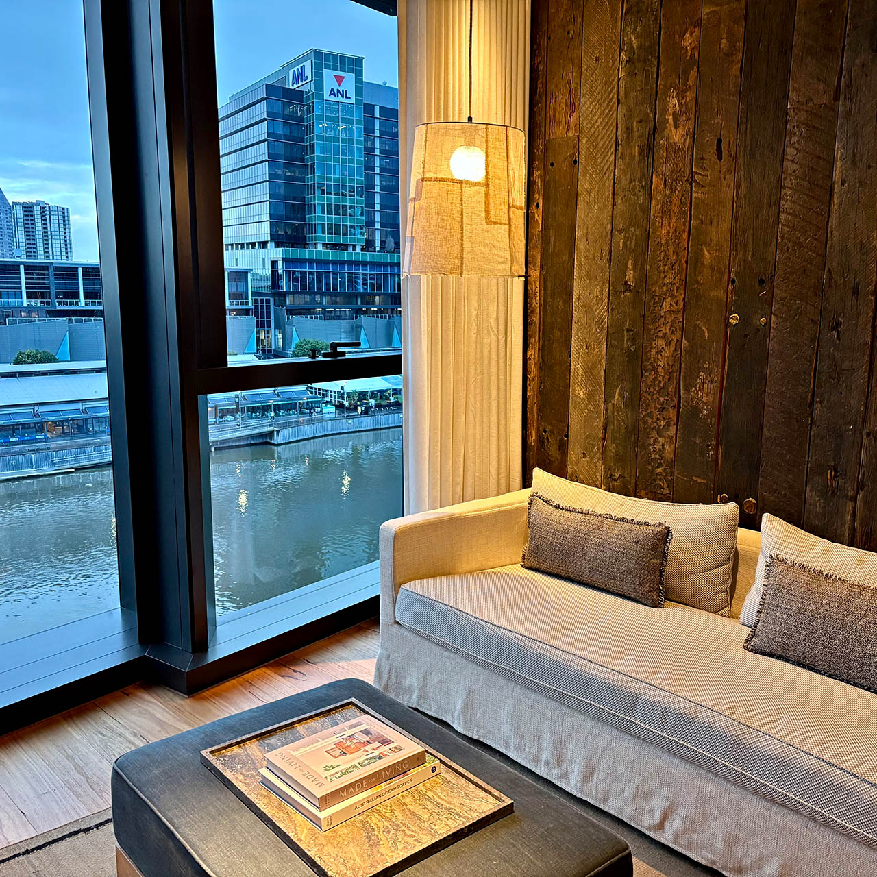 Suite living area at 1 Hotel Melbourne overlooking the Yarra River and Melbourne skyline through floor-to-ceiling windows.