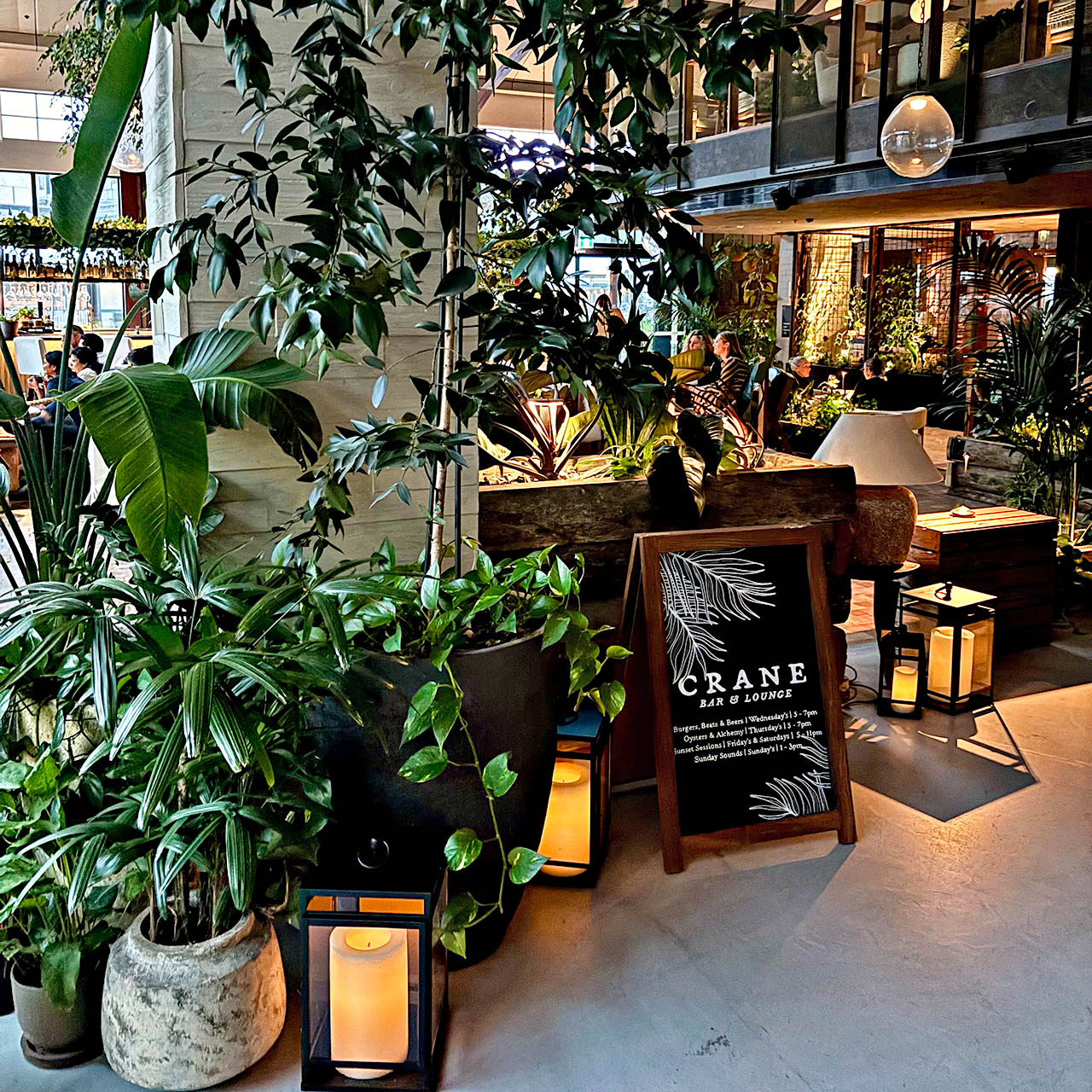 Crane Bar & Lounge at 1 Hotel Melbourne with lush indoor gardens and stylish seating.