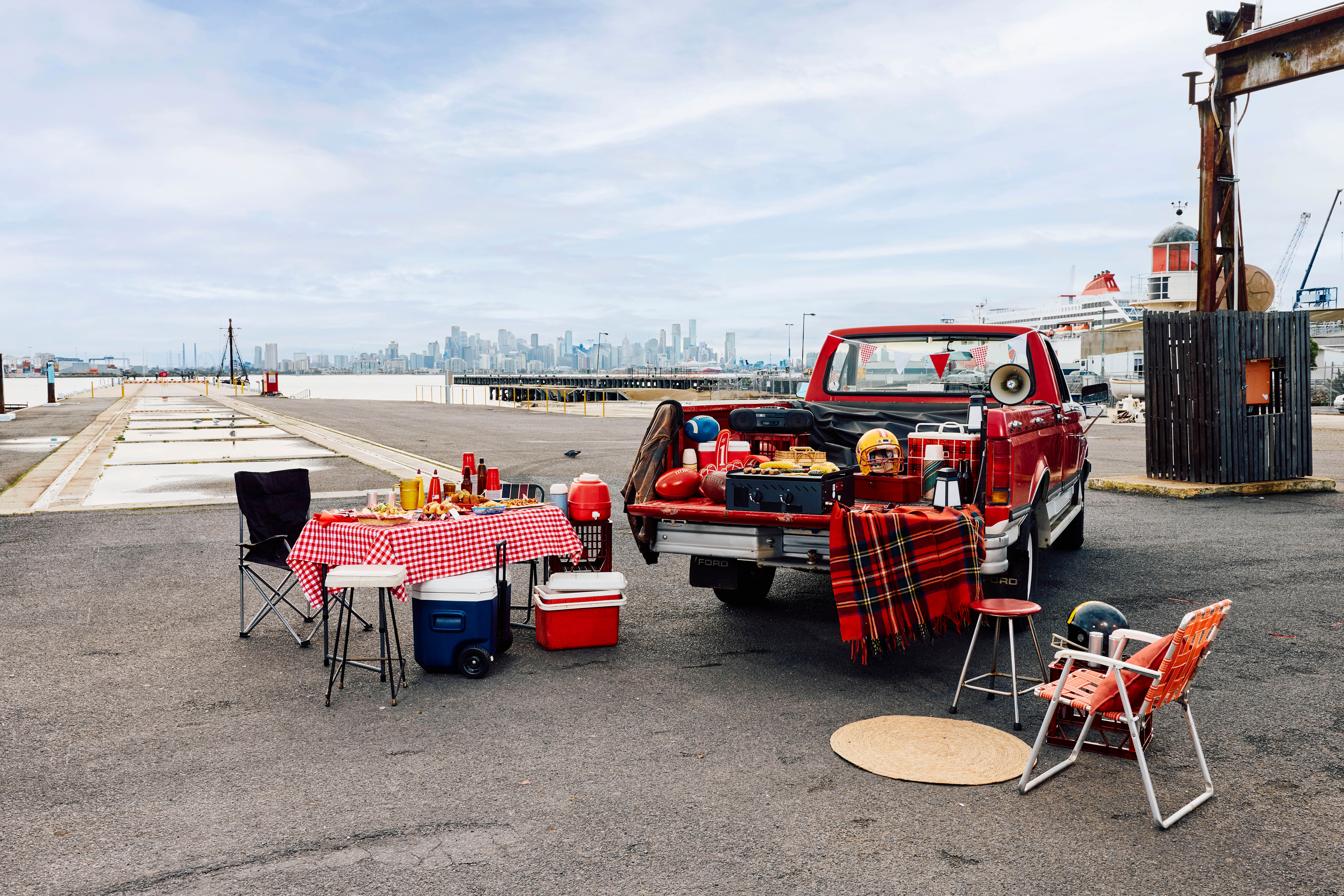 Airbnb Aussie Tailgate setup at Melbourne’s Seaworks with a red pickup truck, barbecue, picnic table and football gear.