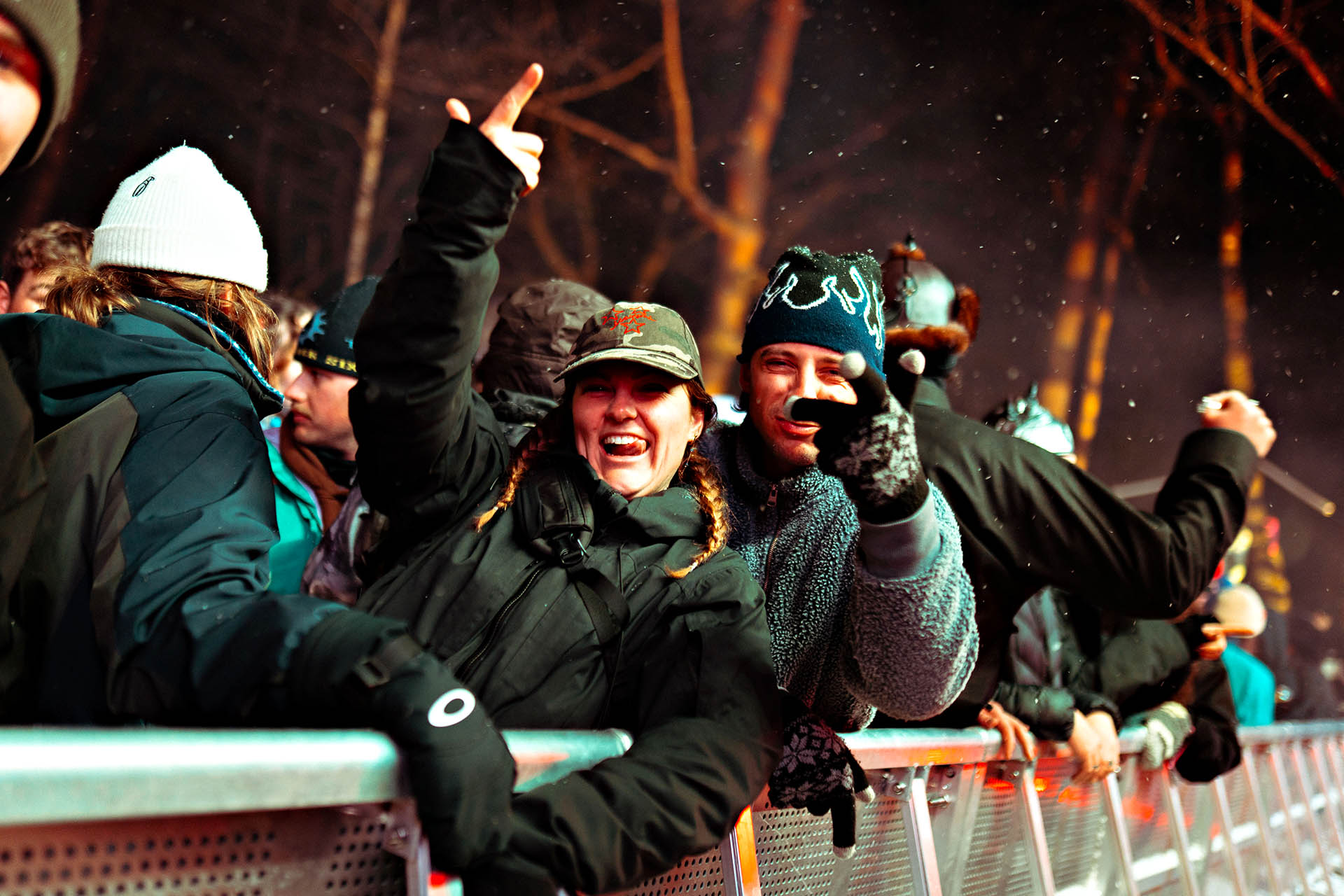 Festivalgoers in winter clothing cheering from the front barrier during a Snow Machine Hakuba concert in Japan.