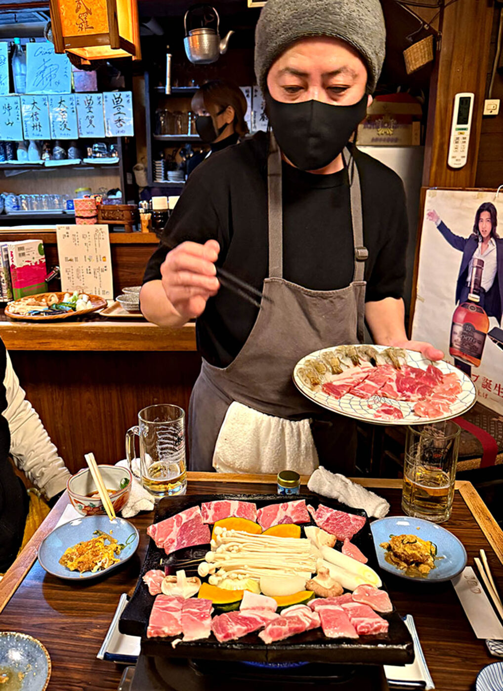Japanese beef and vegetables cooking on a hot ceramic roof tile at a Nagano izakaya.
