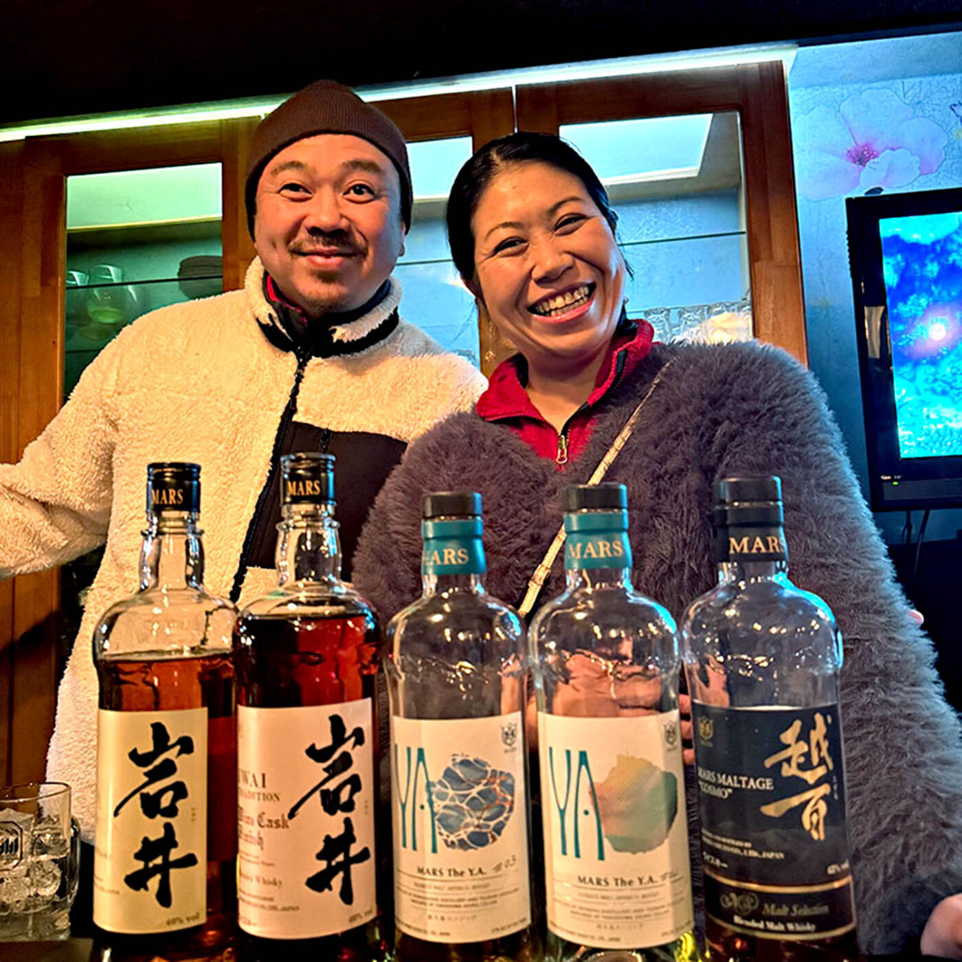Local hosts behind bottles of whisky at a traditional Japanese snack bar in Nagano.