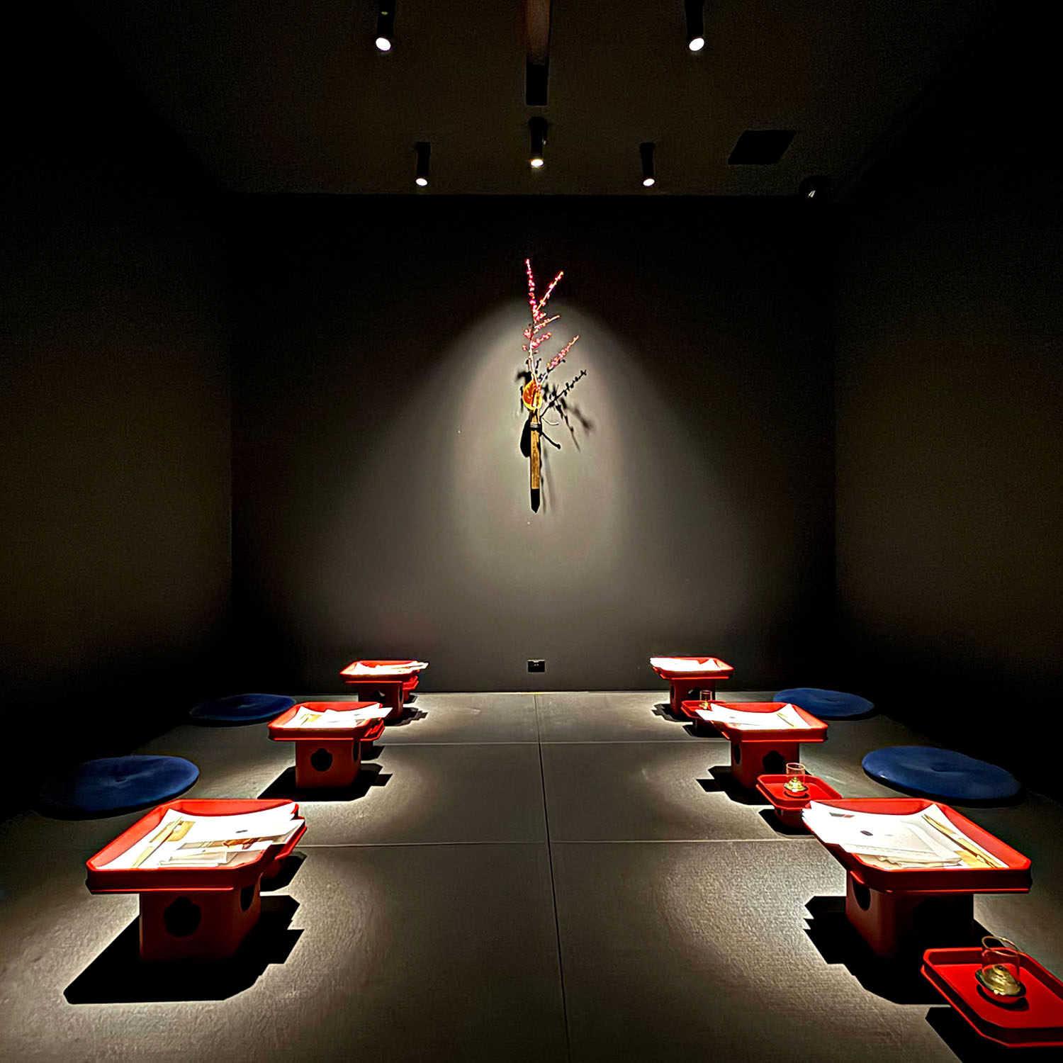 Dark dining room with traditional low red tables at Barrier restaurant in Kanazawa, Japan.