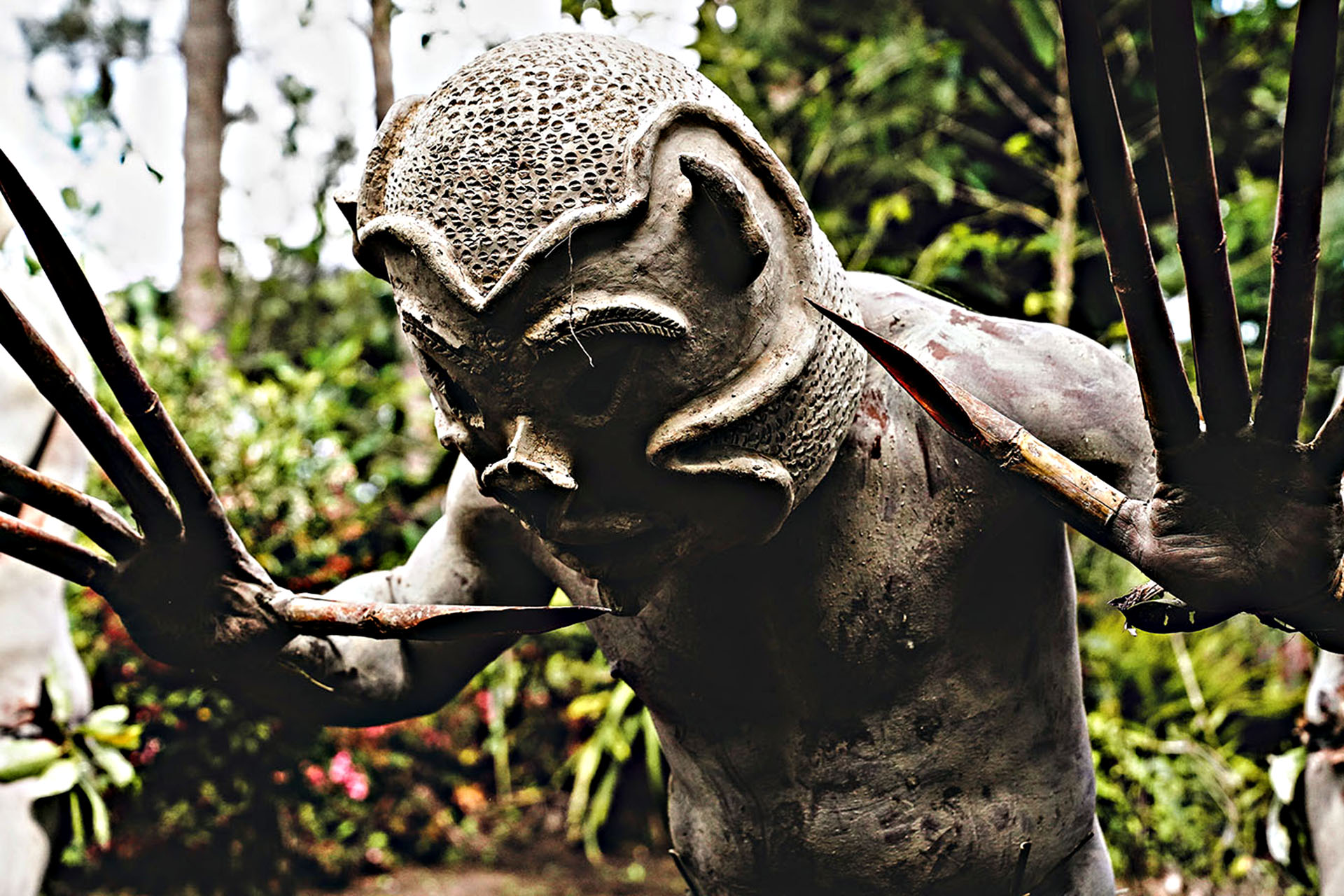 Asaro Mudman wearing a traditional clay mask and carrying a bow and arrow in Papua New Guinea’s Eastern Highlands.