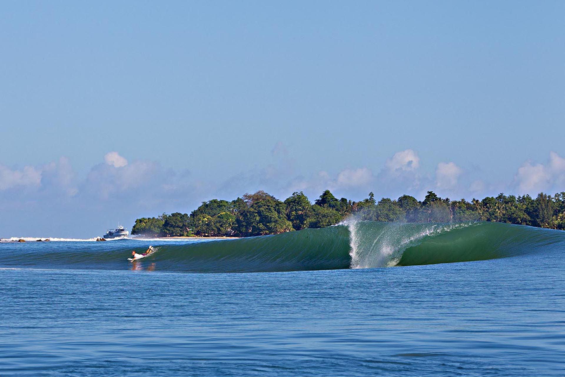 Surfer paddling into a clean tropical wave off the coast of New Ireland, Papua New Guinea.
