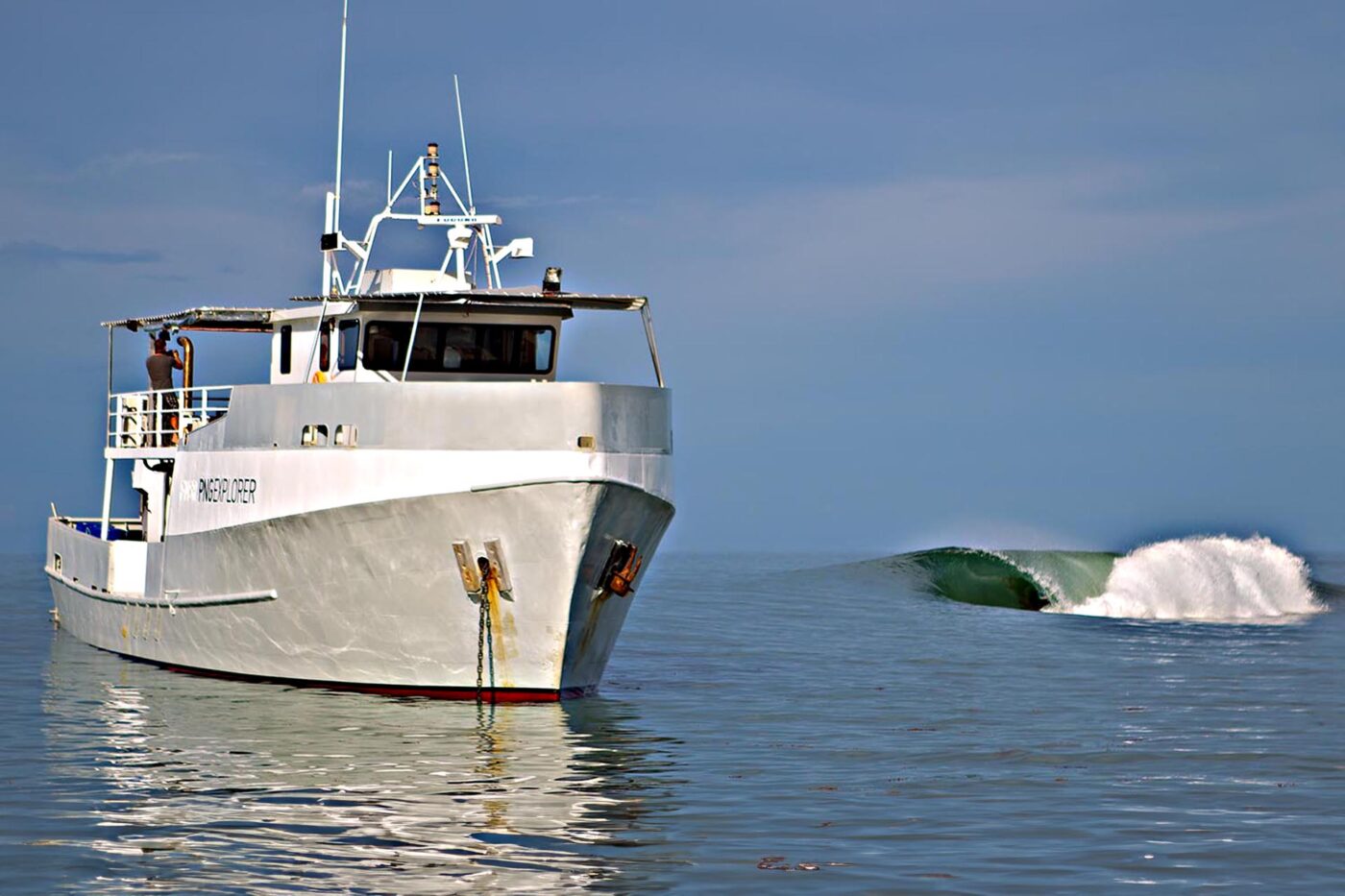PNG Explorer surf charter boat anchored beside an empty reef break in Papua New Guinea.