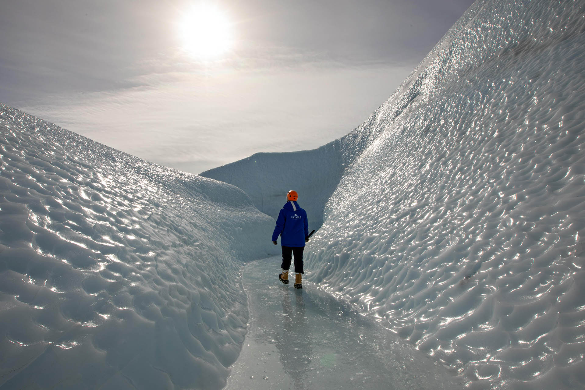Traveller hiking through a deep ice canyon on a glacier expedition in Antarctica.