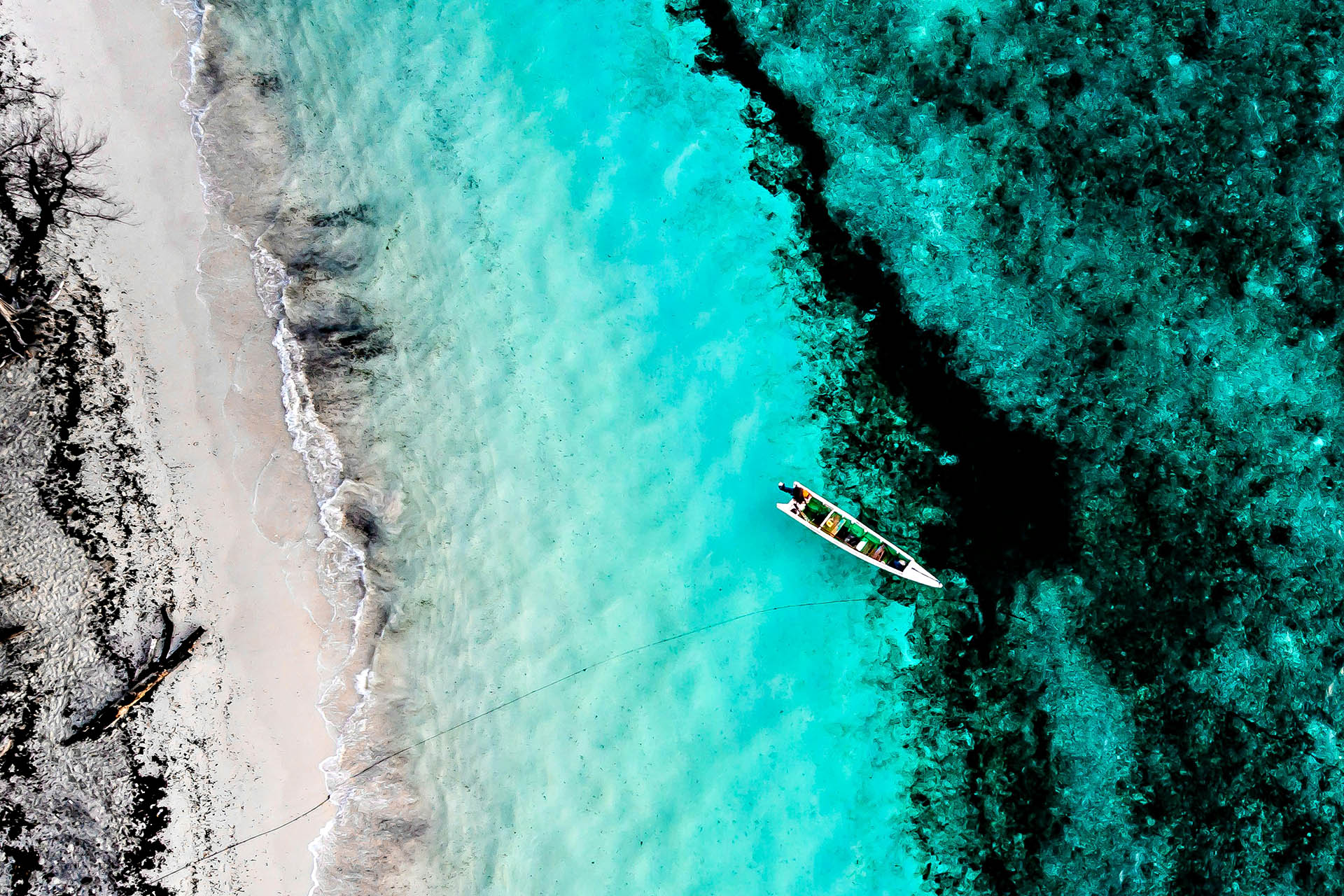 Traditional boat beside turquoise coral reef in Nino Konis Santana National Park.