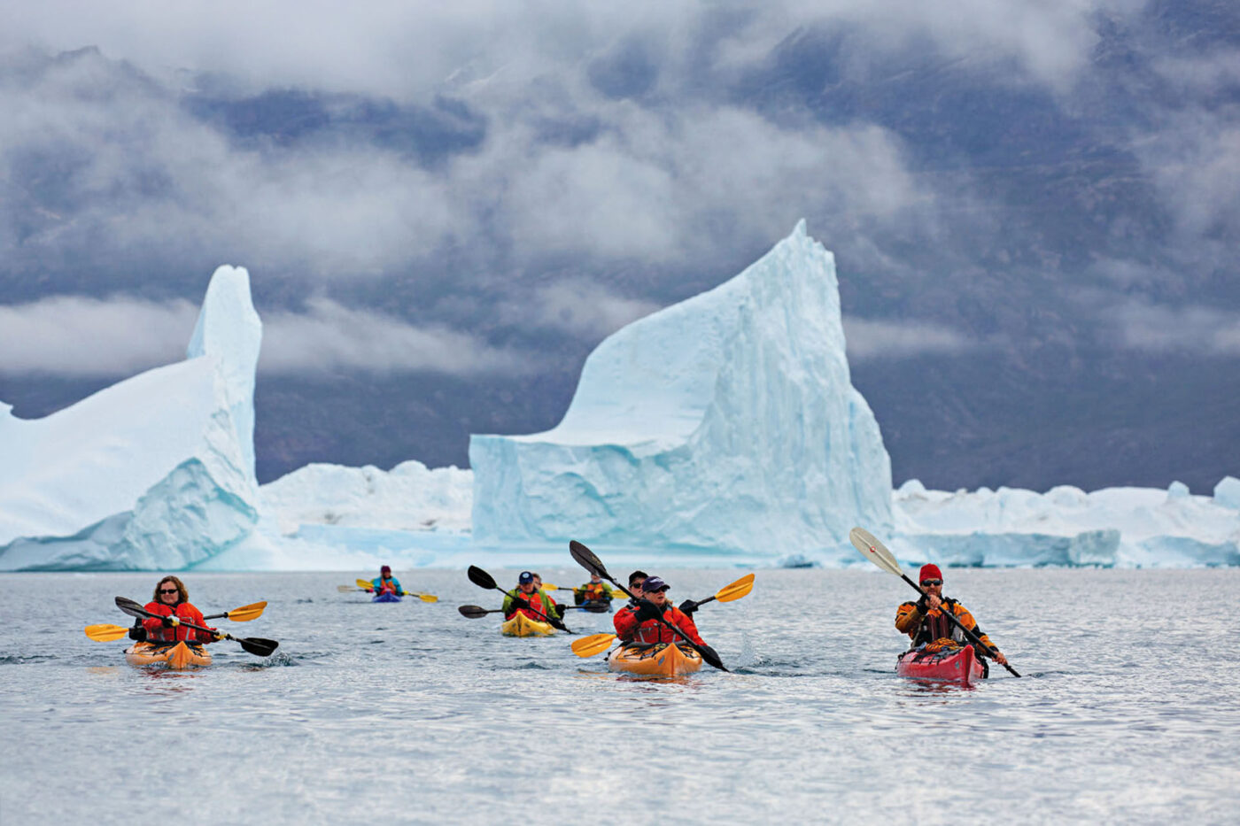 A photo puts the size of the icebergs into perspective as kayakers cruise past.
