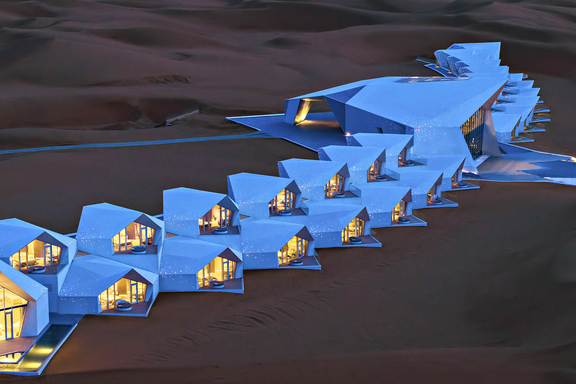 ZhongWei Desert Diamond Hotel glowing among the sand dunes of the Tengger Desert at dusk.