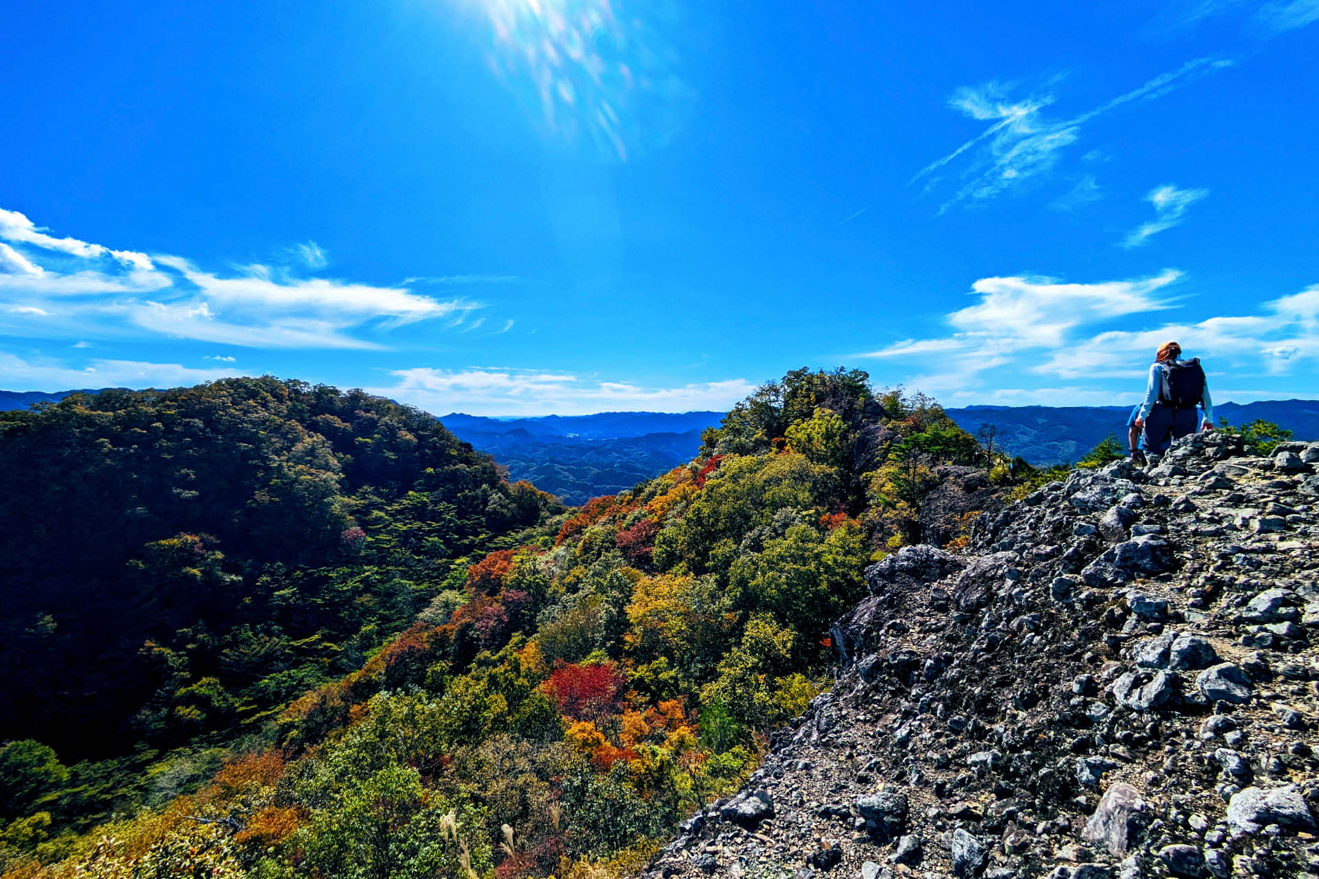 Hiker overlooking autumn-covered mountains on the Hitachi-no-Kuni Long Trail in northern Ibaraki, Japan.