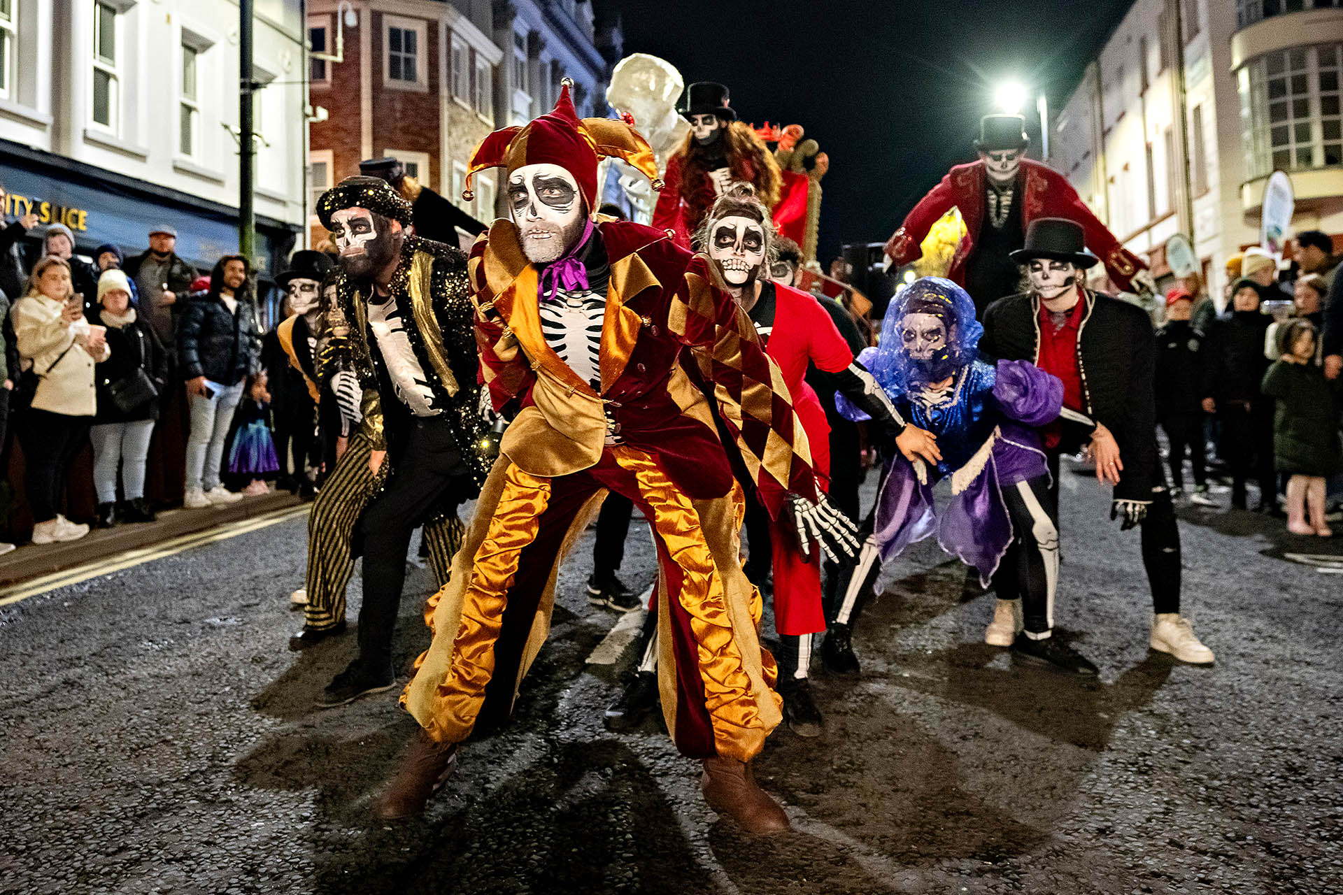 Costumed performers with skeleton face paint parade through Derry during the city’s Halloween festival.