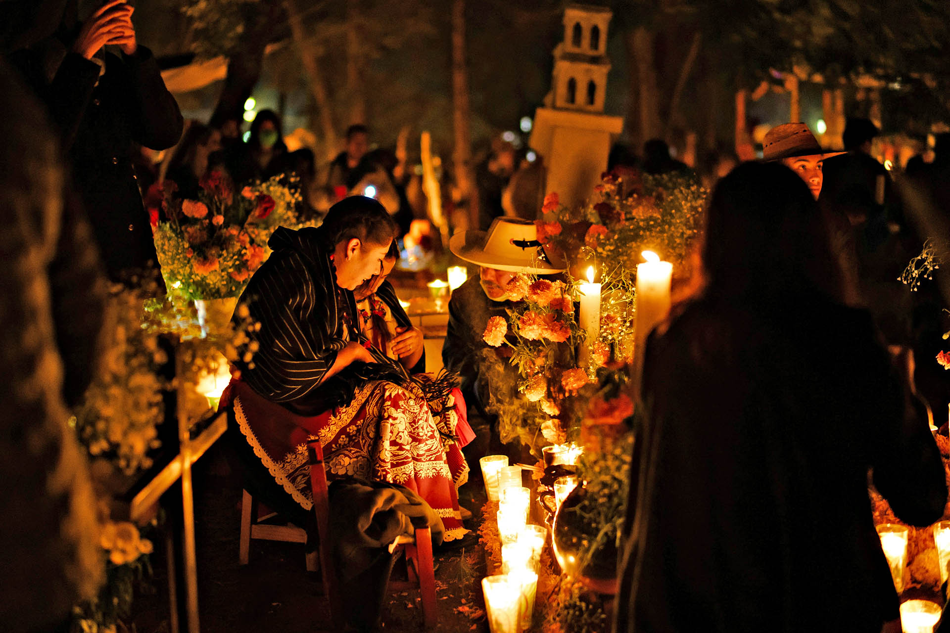 Candlelit Día de Muertos celebrations surrounded by flowers and offerings in Oaxaca, Mexico.